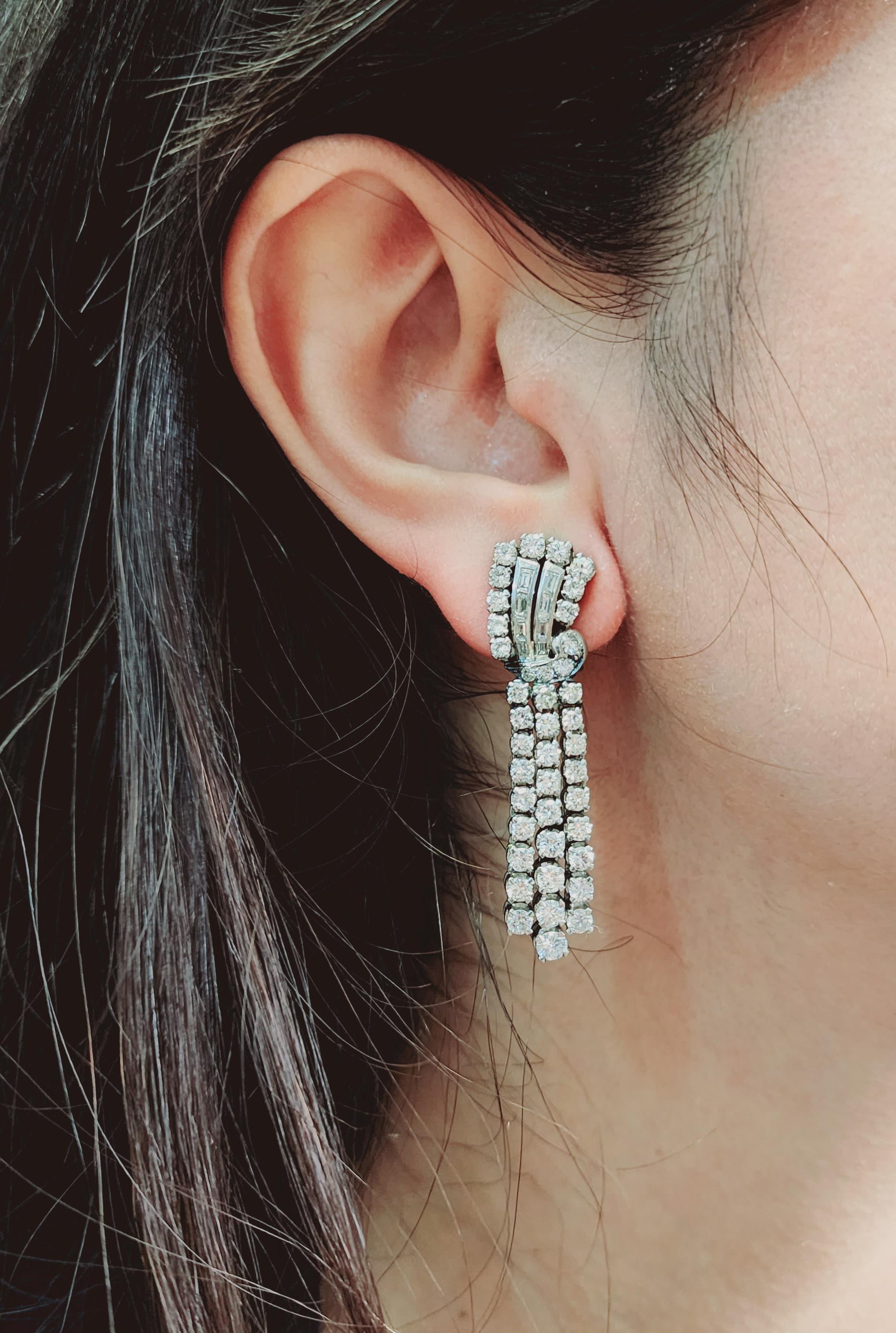 Paire de boucles d'oreilles à pince en platine de style Art déco, ornées de diamants ronds de taille brillant et de diamants baguettes pesant ensemble environ 7,05 carats. Couleur G-H, pureté VS1-2.

Entrez dans le glamour des années folles avec ces
