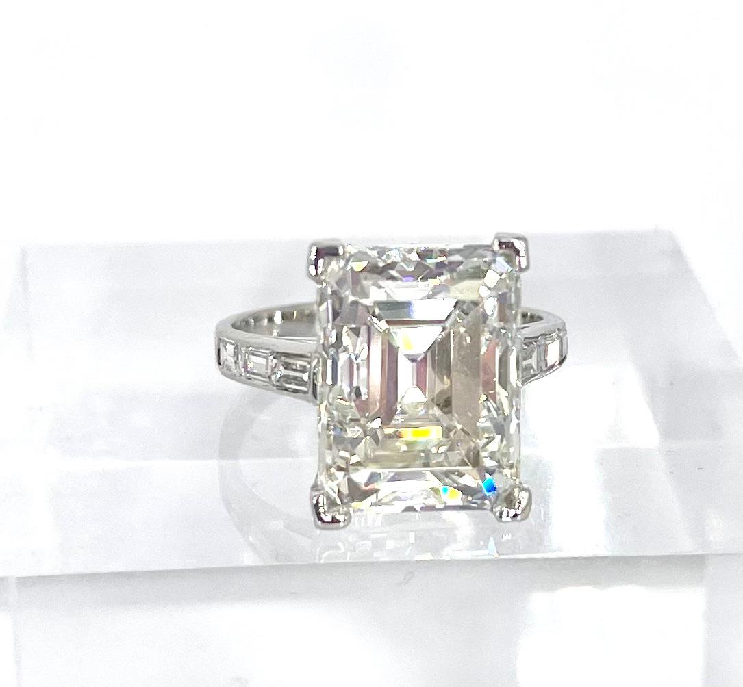 This stunning emerald cut diamond is set in a timeless vintage platinum setting. The center diamond is 7.07 carats, certified by GIA to be I color and VVS2 clarity, report number 2215810746. The delicate basket is embellished with ten tiny round