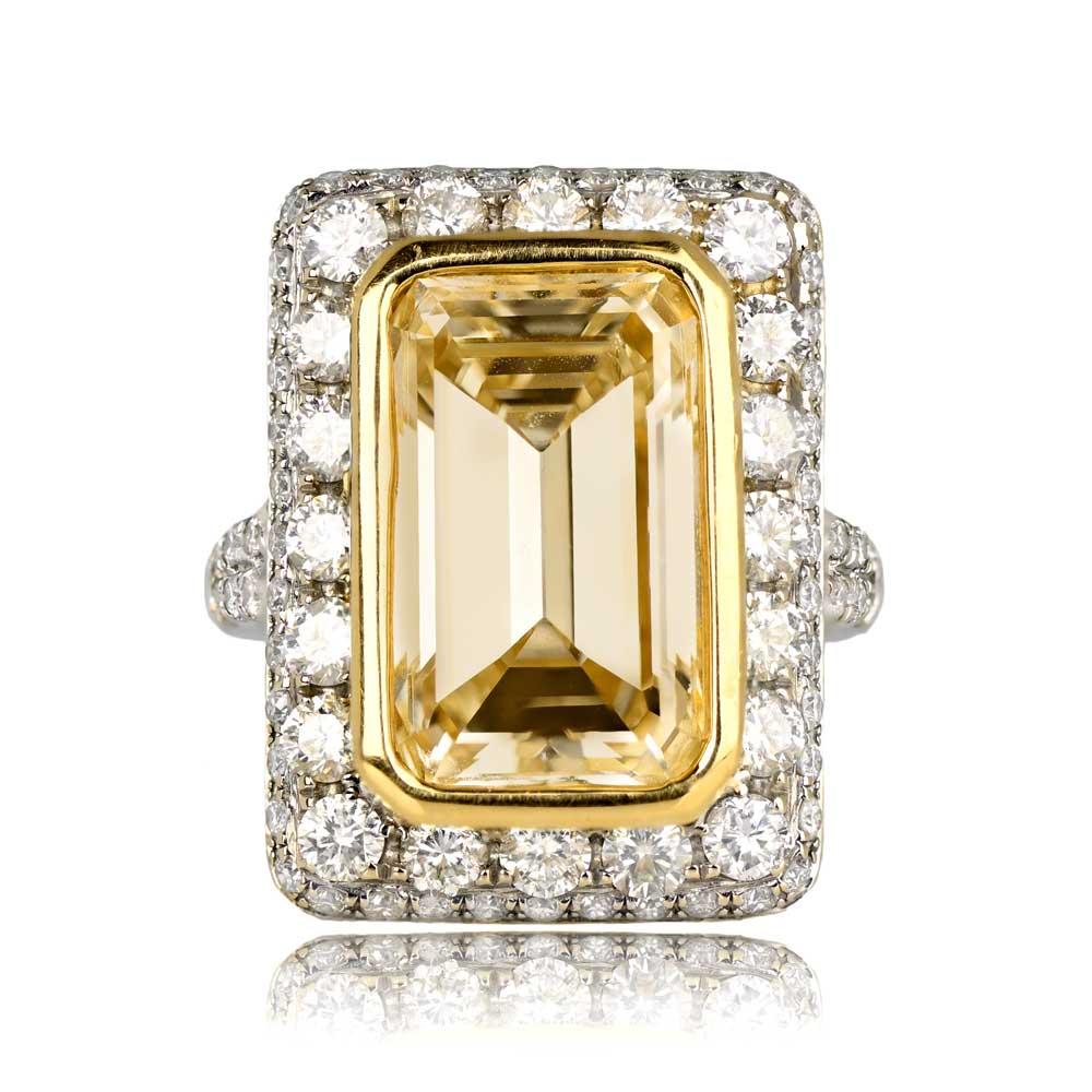 This impressive ring highlights a 7.07-carat Fancy Light Yellow emerald-cut diamond as the centerpiece, encircled by larger round brilliant-cut diamonds and a border of smaller round brilliant-cut diamonds. The split shank is adorned with micro-pave