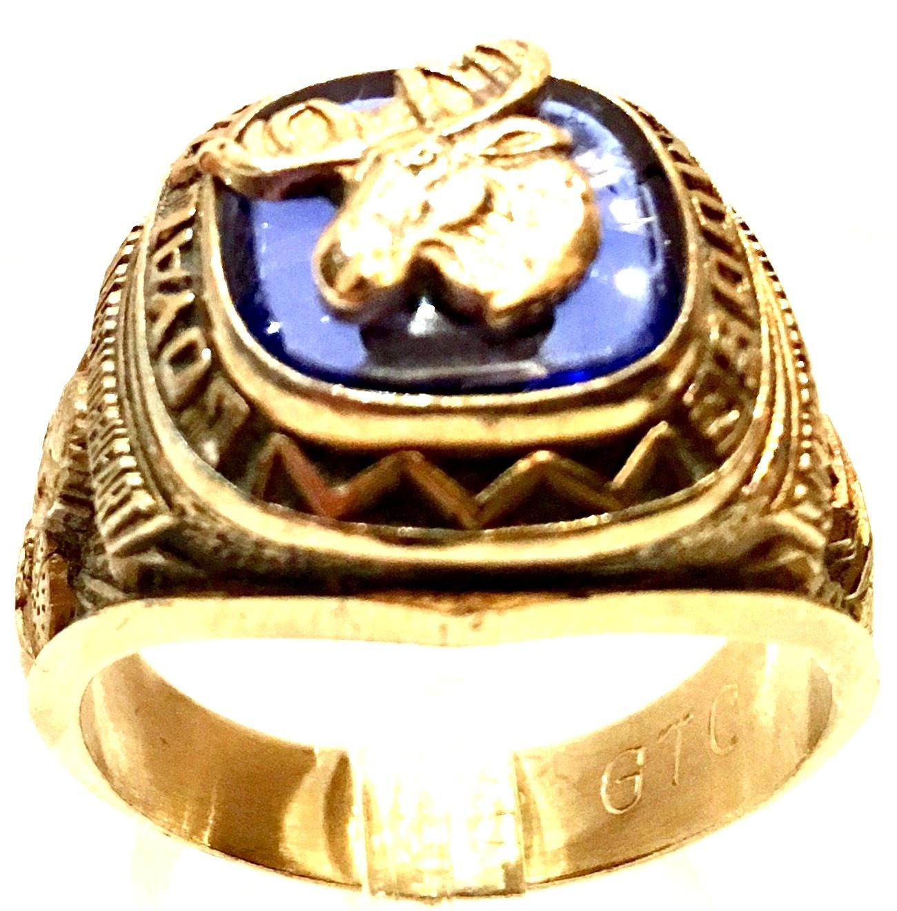 1970's 10 Karat Gold & Blue Glass Synthetic Stone Fraternal Moose Legion Ring. This ring features a cushion shaped slab cut blue clear synthetic stone that has a carved and enameled Legion of the Moose emblem in the center. The stone is bezel set