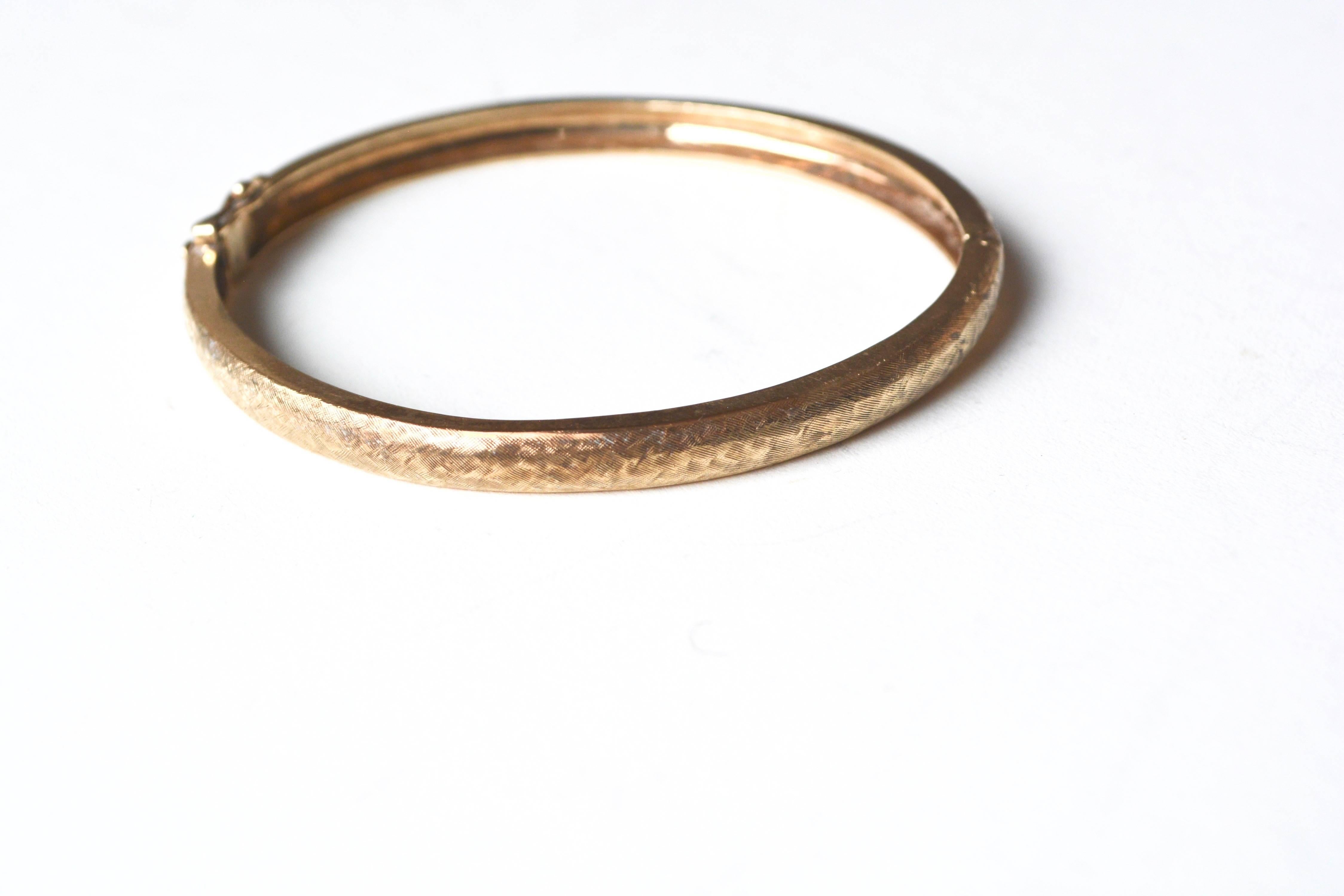 Textured stackable 1970s 14k gold bangle with latch style closure. Not marked, tested. Good overall condition. About 7