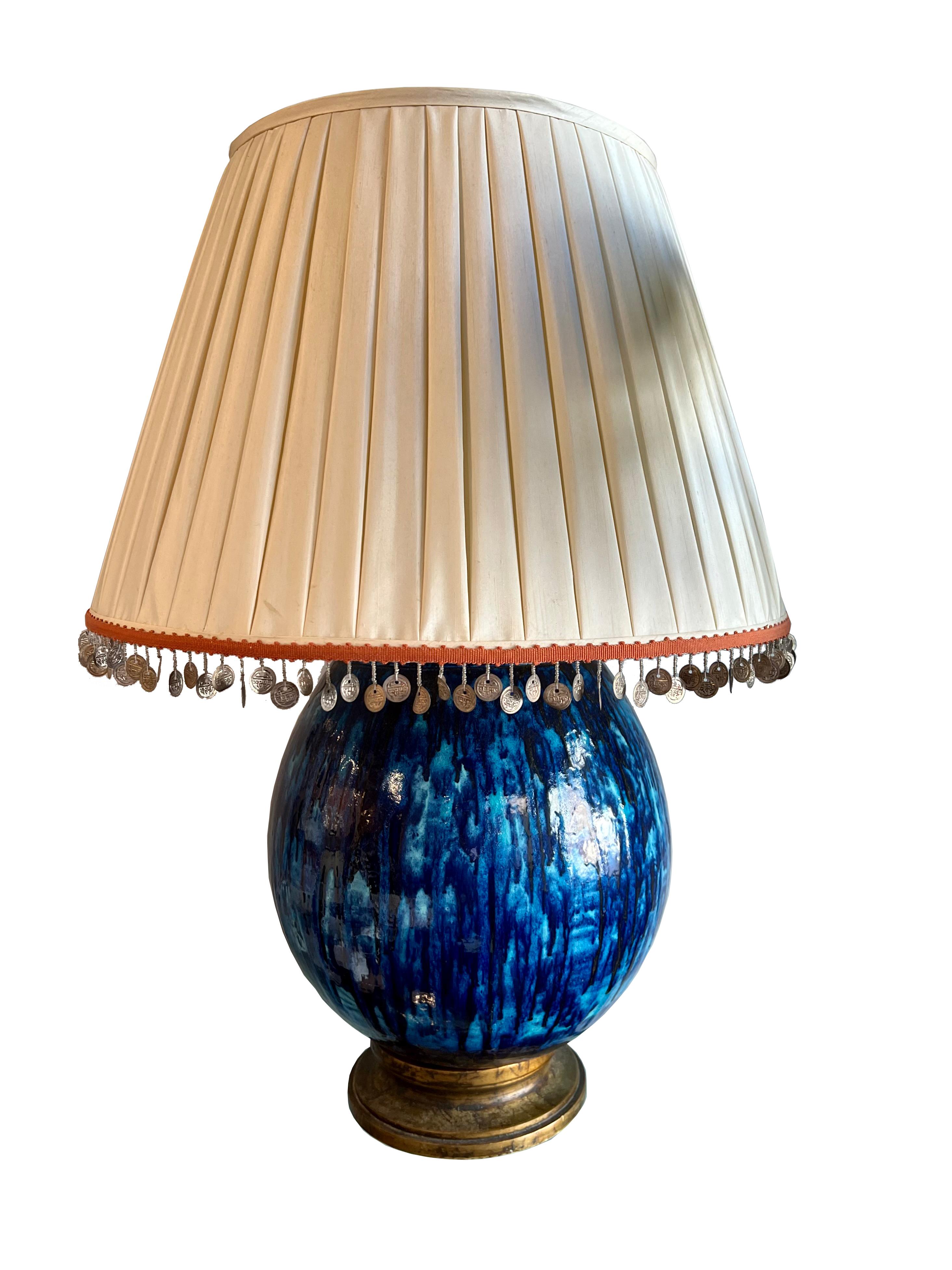Extra-large vintage ceramic blue glazed lamp with custom silk lamp shade.
Lampshade has coin and orange tape trim along the bottom and lamp has a faux brass wood base.

Lamp Dimensions: 18