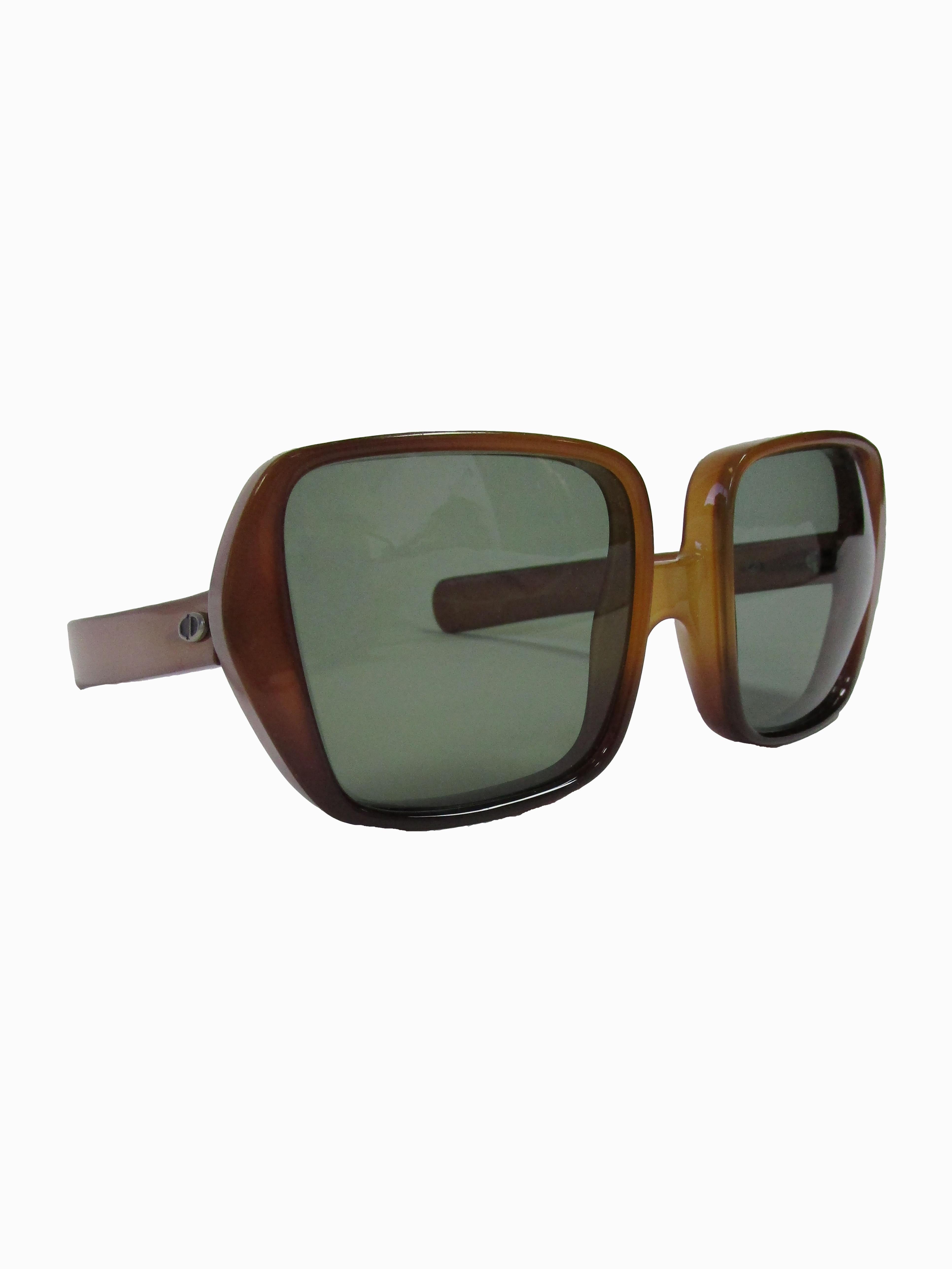 
Fantastic Christian Dior Sunglasses that feature a brutalist style framing with translucent brown optyl acetate and tinted green lenses. Christian Dior was the first designer brand to use optyl, before most sunglasses were made of acetate. Optyl is