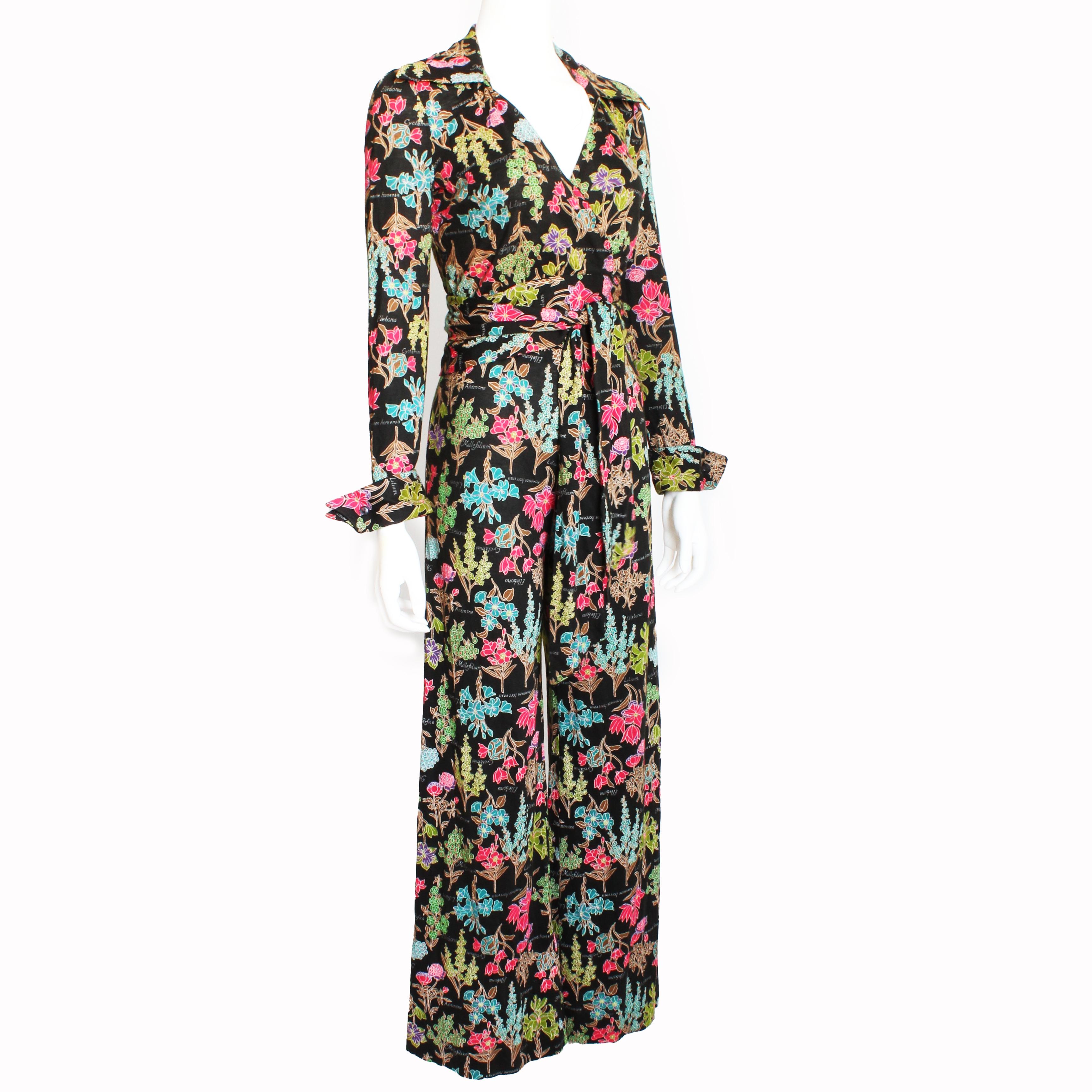 This ensemble was designed by Diane Von Furstenberg in the mid-1970s and includes her signature wrap style as a blouse with matching flared bottom pants.  Made from an acrylic jersey fabric, it features a colorful floral pattern against a black
