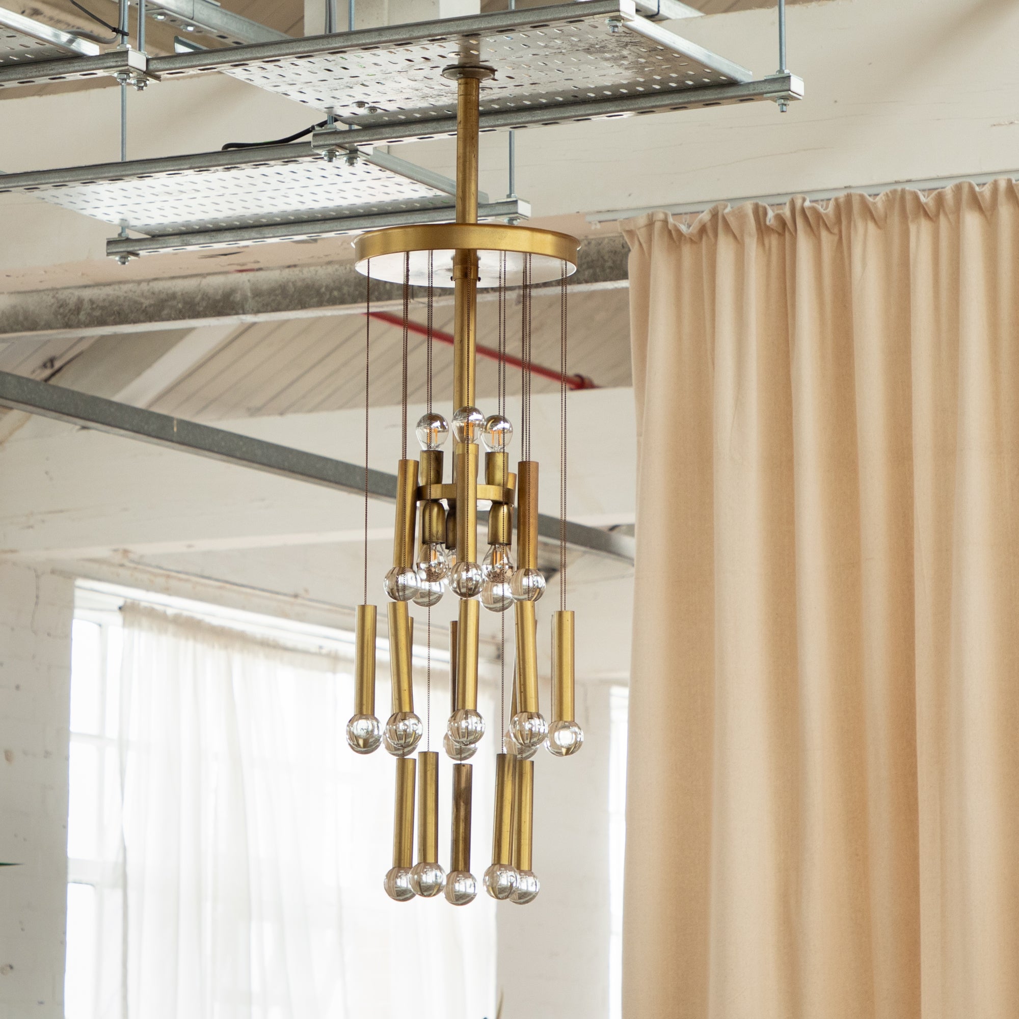1970s brass and glass chandelier. Long brass chains with tubular brass and glass domes. The central section fits to the ceiling and holds four bulb holders to the upper level. The light reflects and refracts beautifully on to the lower glass