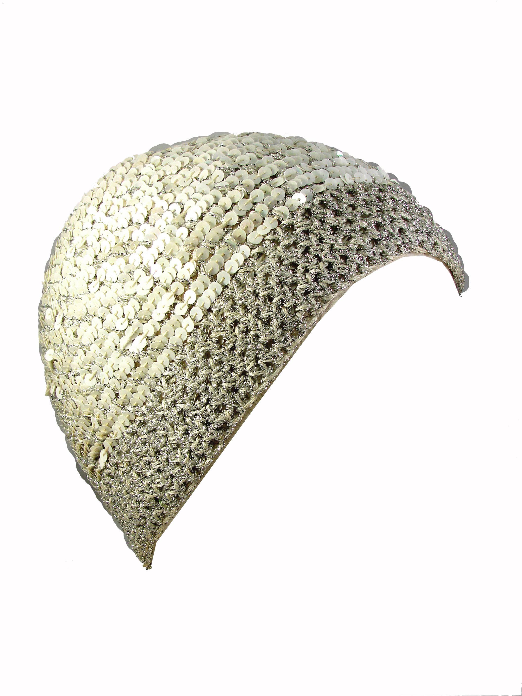 Here's an incredible sequins hat from Halston circa 1971.  Made from white sequins and a silver metallic thread knit, this skull cap features two elasticized laces, which enable one to adjust the bottom band and change its shape.  Tagged HALSTON and