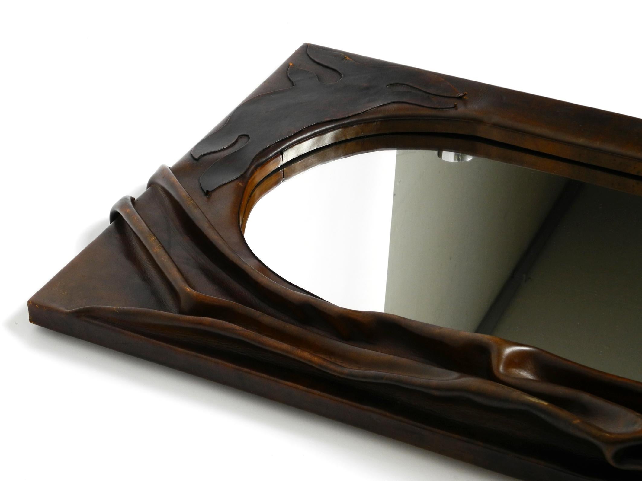 European 70s large wooden wall mirror with an elaborate and thick flowing leather cover  For Sale