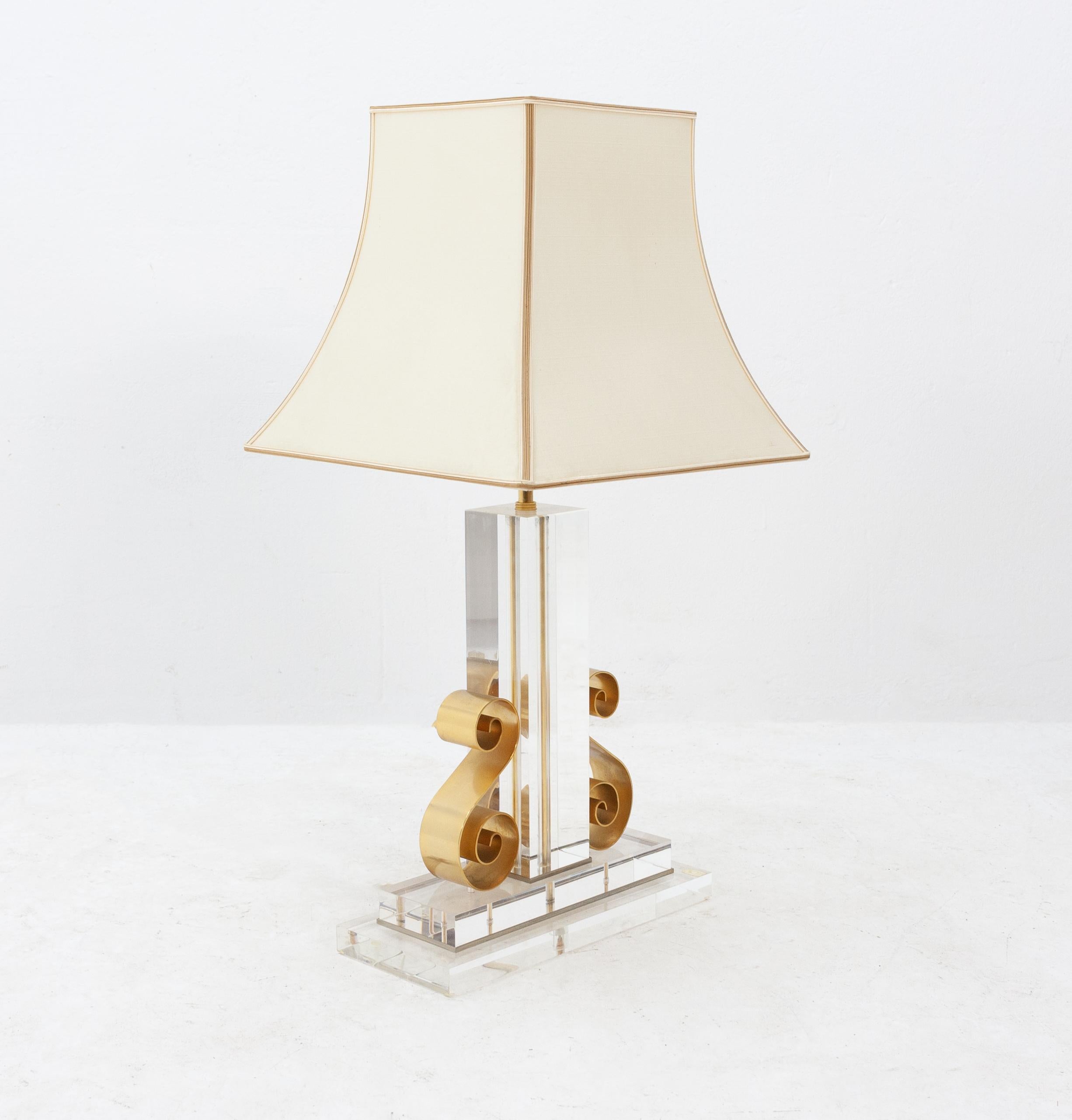 Hollywood Regency Lucite table lamp. Sold by Cascades Scheveningen, Holland 1970s
Solid Lucite with two golden aluminum S shape ornaments. With the original silk hood.
Very good condition overall.