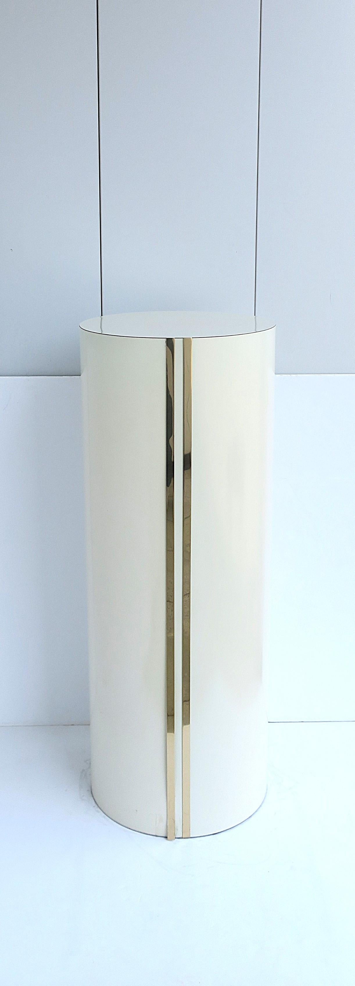 A cylindrical off-white/cream laminate pedestal with gold brass-plate accent, '70s Modern/Post-Modern period, circa late-20th century, 1970s. Piece has a weighted bottom for stability. 