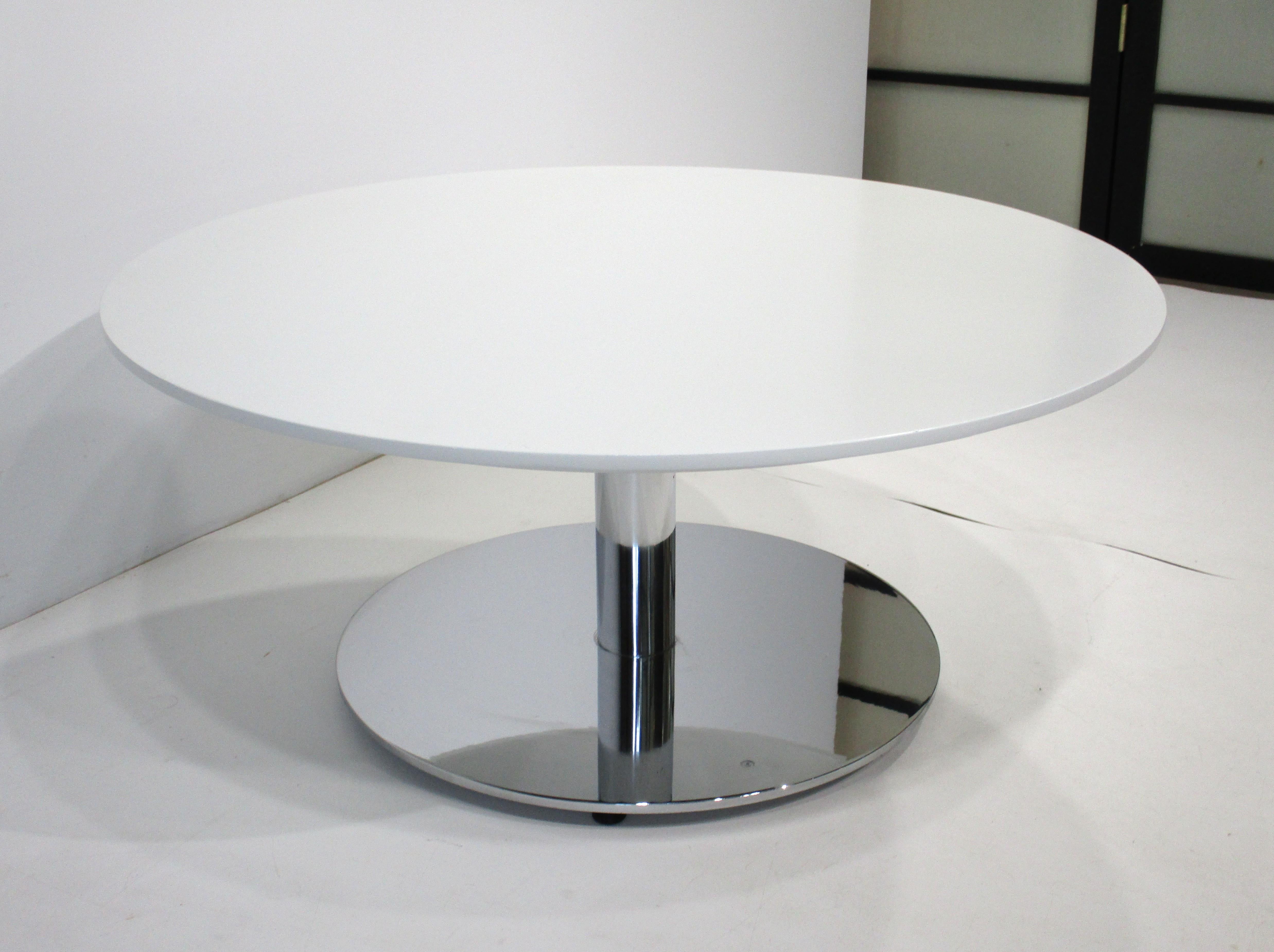 A very well-crafted heavy steel chrome plated based coffee table with beveled edged white painted wood round top. Manufactured in the manner of designer Nicos Zographos and Zographos Designs LTD. known for their high-end furniture from the 1970's