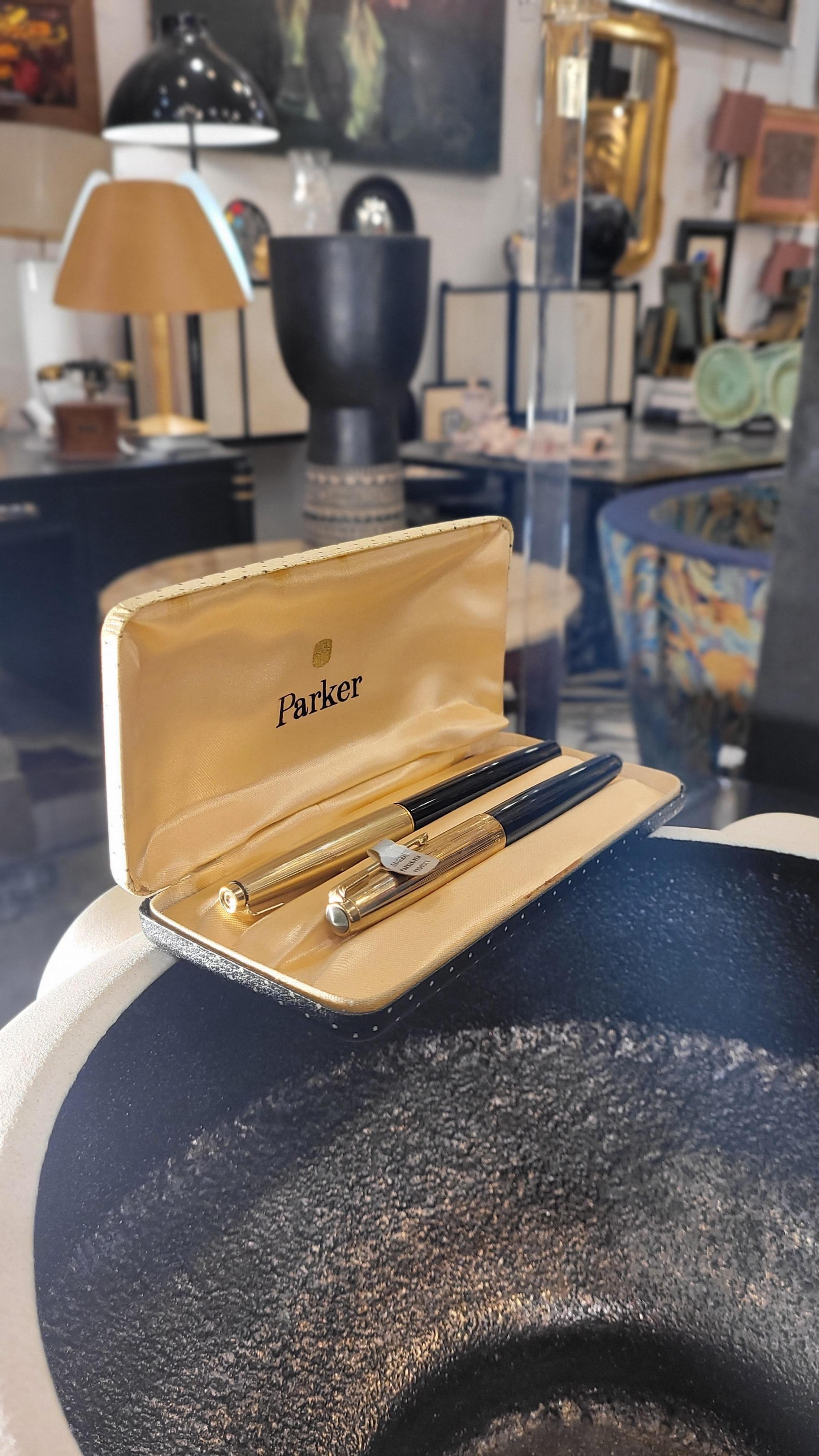 70s Parker fountain pen set, gold plated, case
Fountain pen manufactured in the United States by Parker in the mid-sixties.
Pair of PARKER 45 CUSTOM fountain pens. Gold plated and black plastic. 14 Kt nib. Converter. 1965. USA.
In its original box.