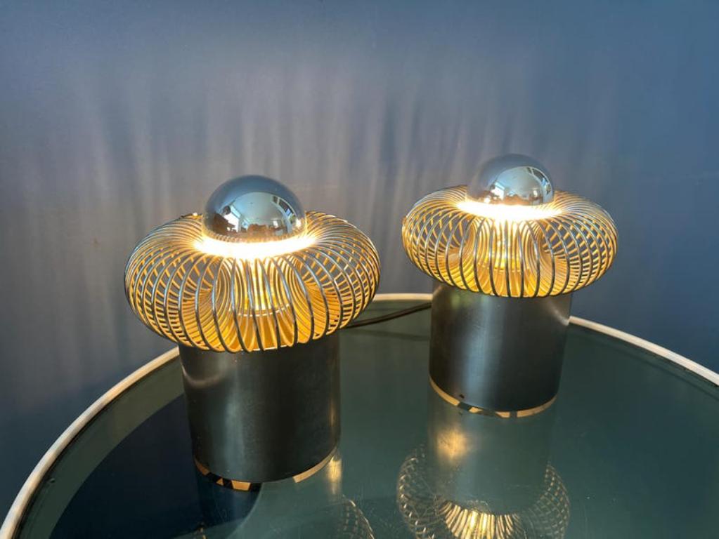 Ensemble de lampes de bureau Philippe Rogier pour la Galerie Oxar. Le design de la pièce incorpore de manière ludique des anneaux en spirale en acier, qui sont serrés autour des ampoules en demi-miroir. La pièce est livrée avec deux ampoules