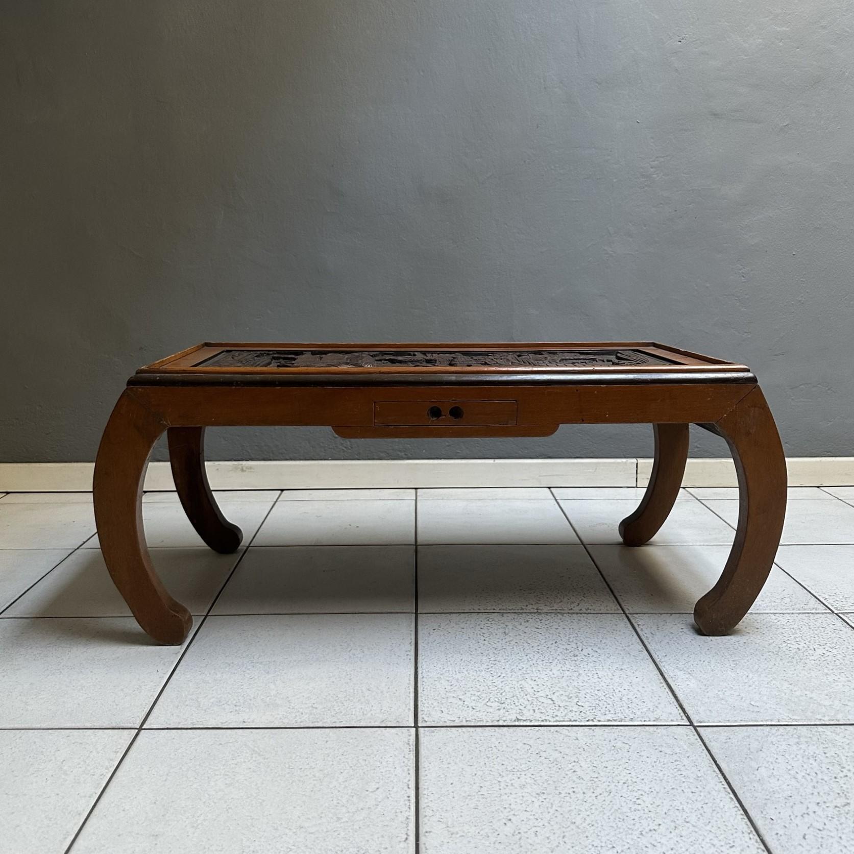 Table basse rectangulaire des années 70, fabrication chinoise.
La structure est en bois incrusté de décorations orientales typiques, probablement utilisée comme table à thé.
La table possède un petit tiroir sur le devant. Sur la photo, vous pouvez