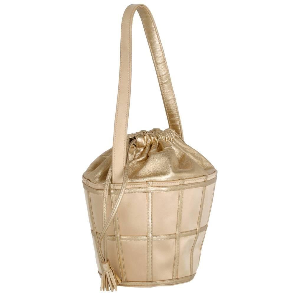 Gold-tone leather René Caovilla bucket bag with silk satin details. Drawstrings closure with tassels. Logoed silk lining and inner pocket.

Measurements
Heigh: 12 cm
Width: 24 cm
Depth: 10 cm
Shoulder strap: 43 cm

Product code: X5248

Notes: The