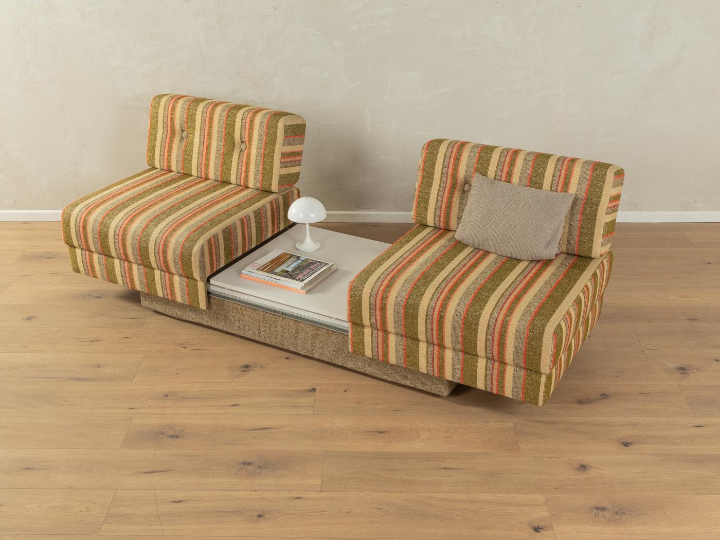 Supercooles Schlafsofa aus den 1970er Jahren mit dem originalen bunten Bezug in Grün-, Beige-, Braun- und Orangetönen und einem Ablagefach mit aufklappbarer Tischplatte mit originaler Formica-Beschichtung in Weiß, das als Couchtisch genutzt werden