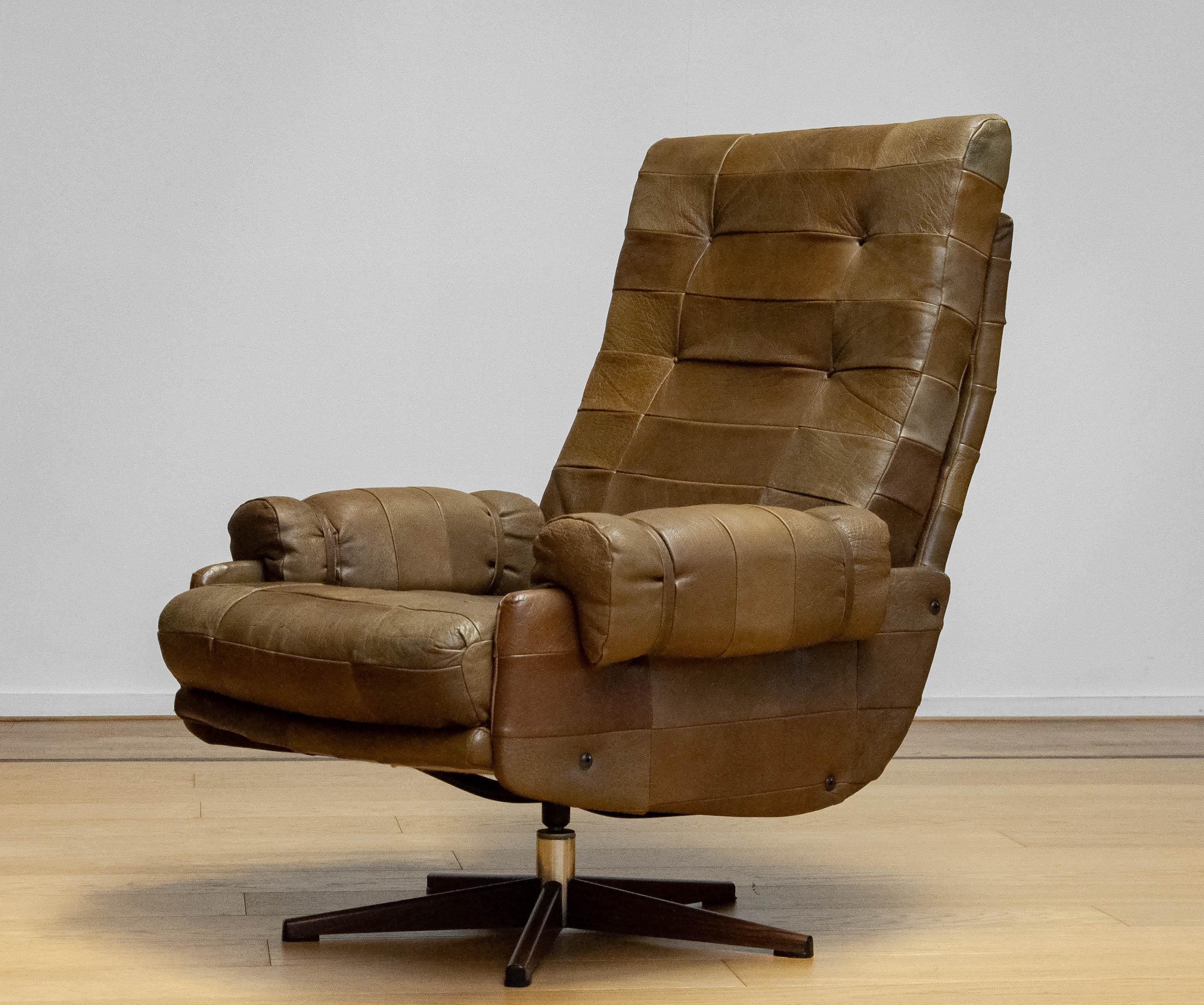 Fauteuil pivotant extrêmement confortable d'Arne Norell pour Norell Möbler AB en Suède. La chaise est recouverte d'un magnifique et robuste cuir de buffle vert olive (patchwork). La chaise offre un excellent soutien et est parfaitement adaptée aux