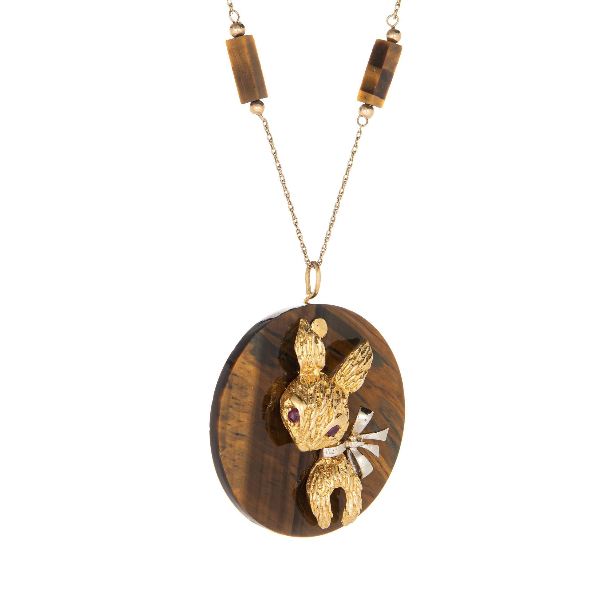 Finely detailed retro Rabbit medallion necklace crafted in 14 karat yellow gold (circa 1970s). 

Two estimated 0.08 carat rubies total an estimated 0.16 carats. The tigers eye medallion measures 45mm diameter (1.77 inches). A total of 8 tigers eye