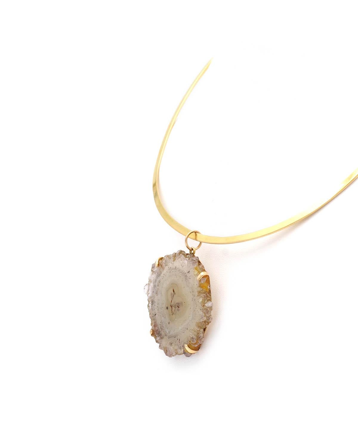 Collana in quarzo torque anni '70 in oro 18 carati. Questa collana presenta un collare rigido e piatto in oro e un ciondolo in quarzo e agata. Il ciondolo è incastonato con quattro punte e presenta varie sfumature di grigio e bianco. Collana con