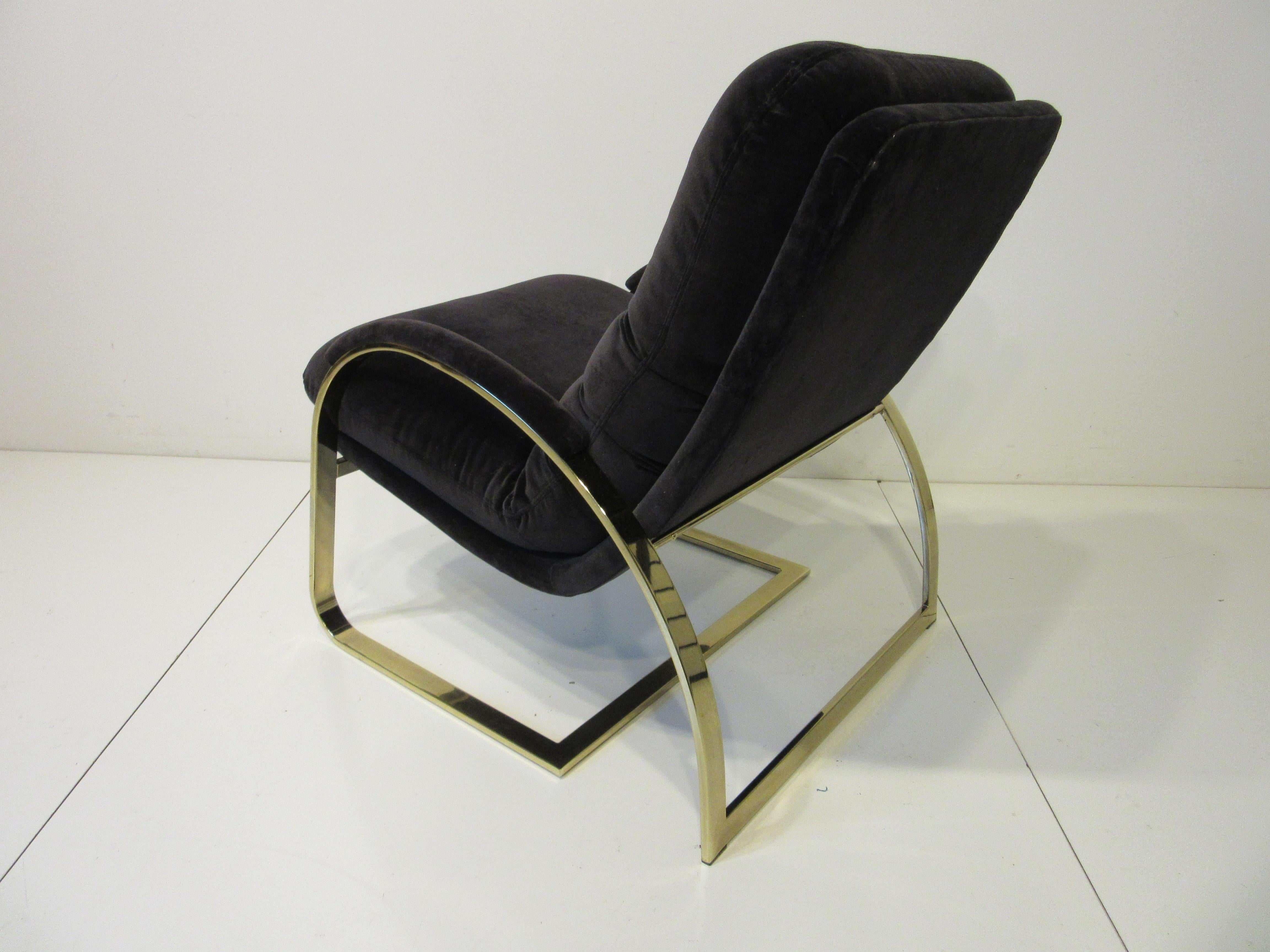 A sculptural brass framed lounge chair with padded arms and tufted back cushion having a higher back for comfort . The fabric is a very dark eggplant color in a soft velvet in the manner of Leon Pace and the Pace collection.