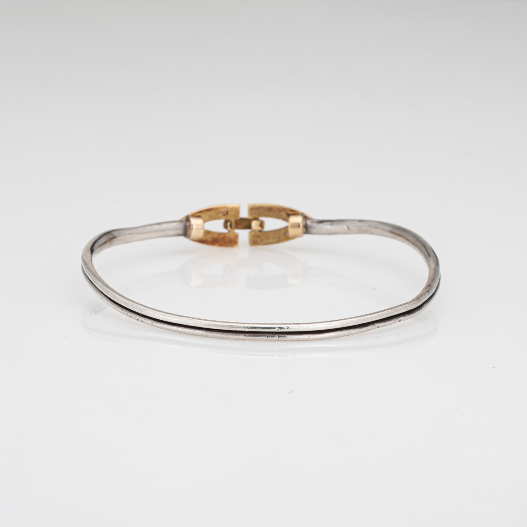 Stylish vintage Cartier bangle bracelet crafted in sterling silver & 18k yellow gold (circa 1970s).  

The sterling silver bangle features a hook closure crafted in 18k yellow gold. The bangle is great worn alone or layered. The bangle is designed