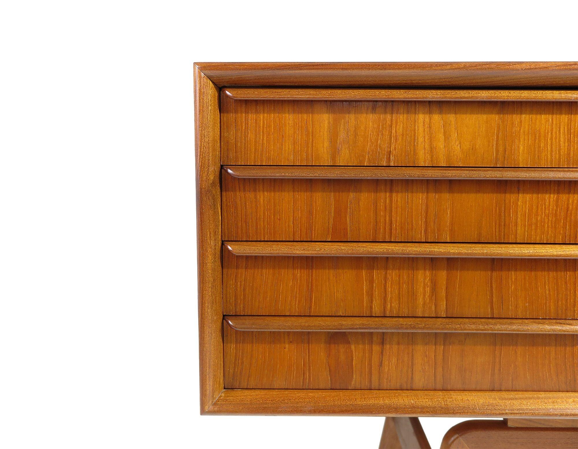 La credenza danese, realizzata a mano in teak di vecchia data, presenta quattro cassetti e una coppia di ante scorrevoli con ampie venature abbinate ai libri, che si aprono per rivelare un interno in teak con ripiani regolabili. Questa attenzione ai