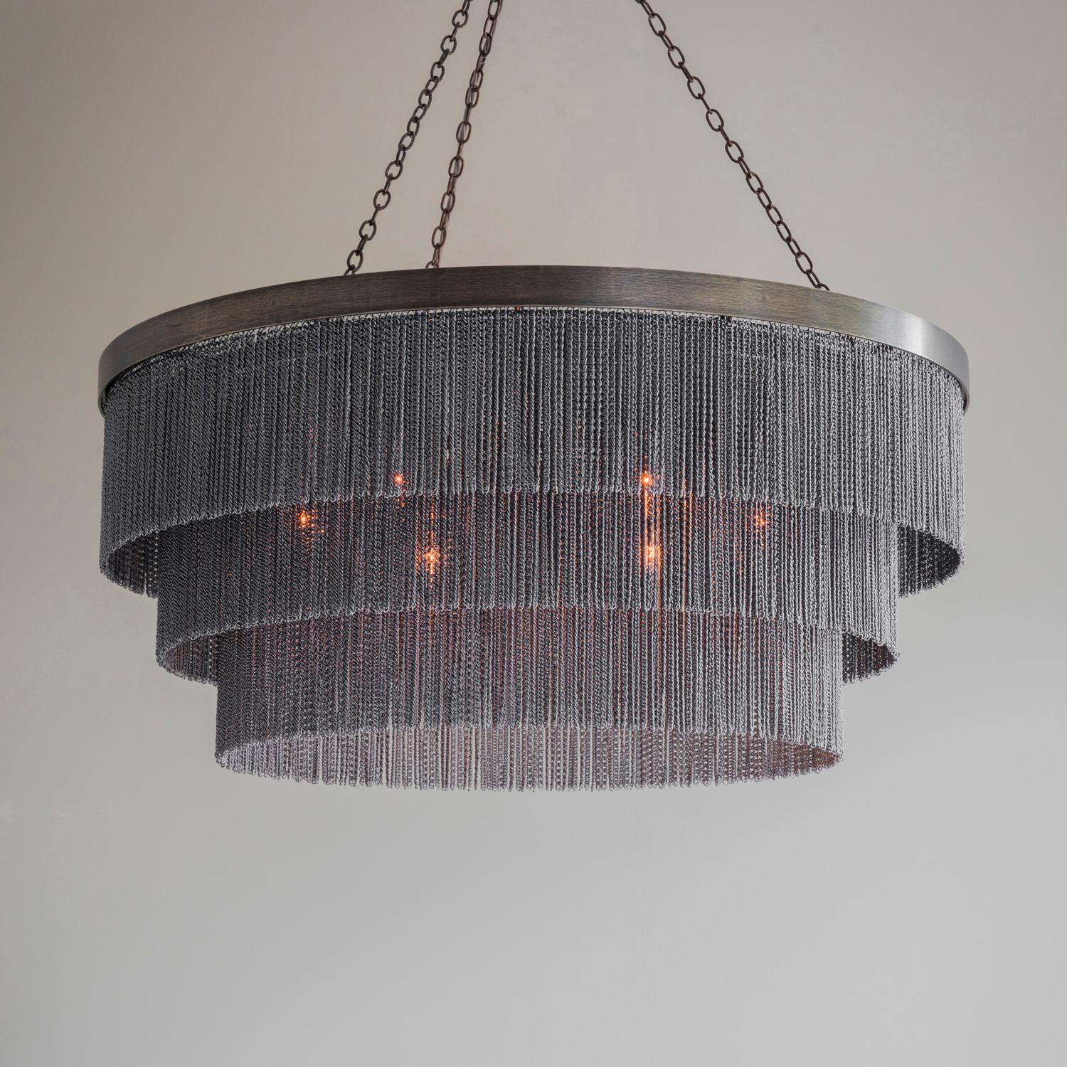 Contemporary chandelier with three shallow tiers of delicate chain strands and handcrafted metalwork. Available in bronze, gold or flat nickel metalwork with either black or silver decorative chain.

Designed and handmade by Tigermoth Lighting on