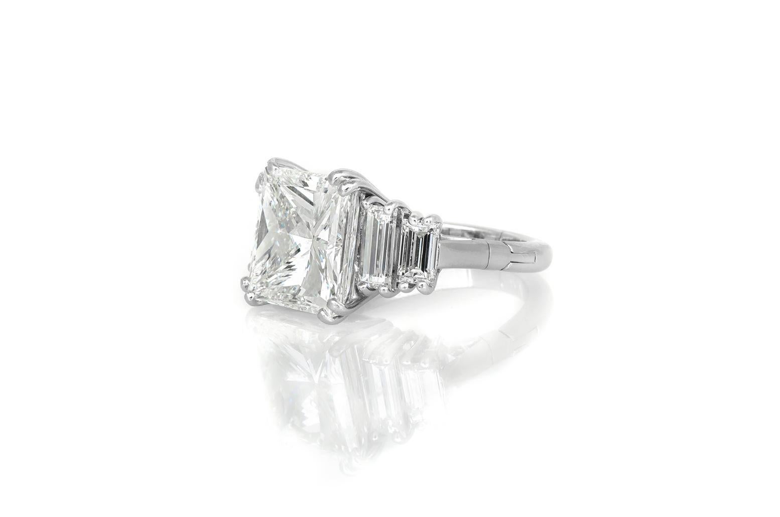 Fein in Handarbeit in Platin mit einem GIA-zertifizierten Princess-Cut-Center Diamond mit einem Gewicht von 7,11 Karat, J Farbe, SI1 Klarheit, GIA # 16162892.
Der Ring ist mit 4 Baguette-Diamanten mit einem Gesamtgewicht von ca. 1,20 Karat