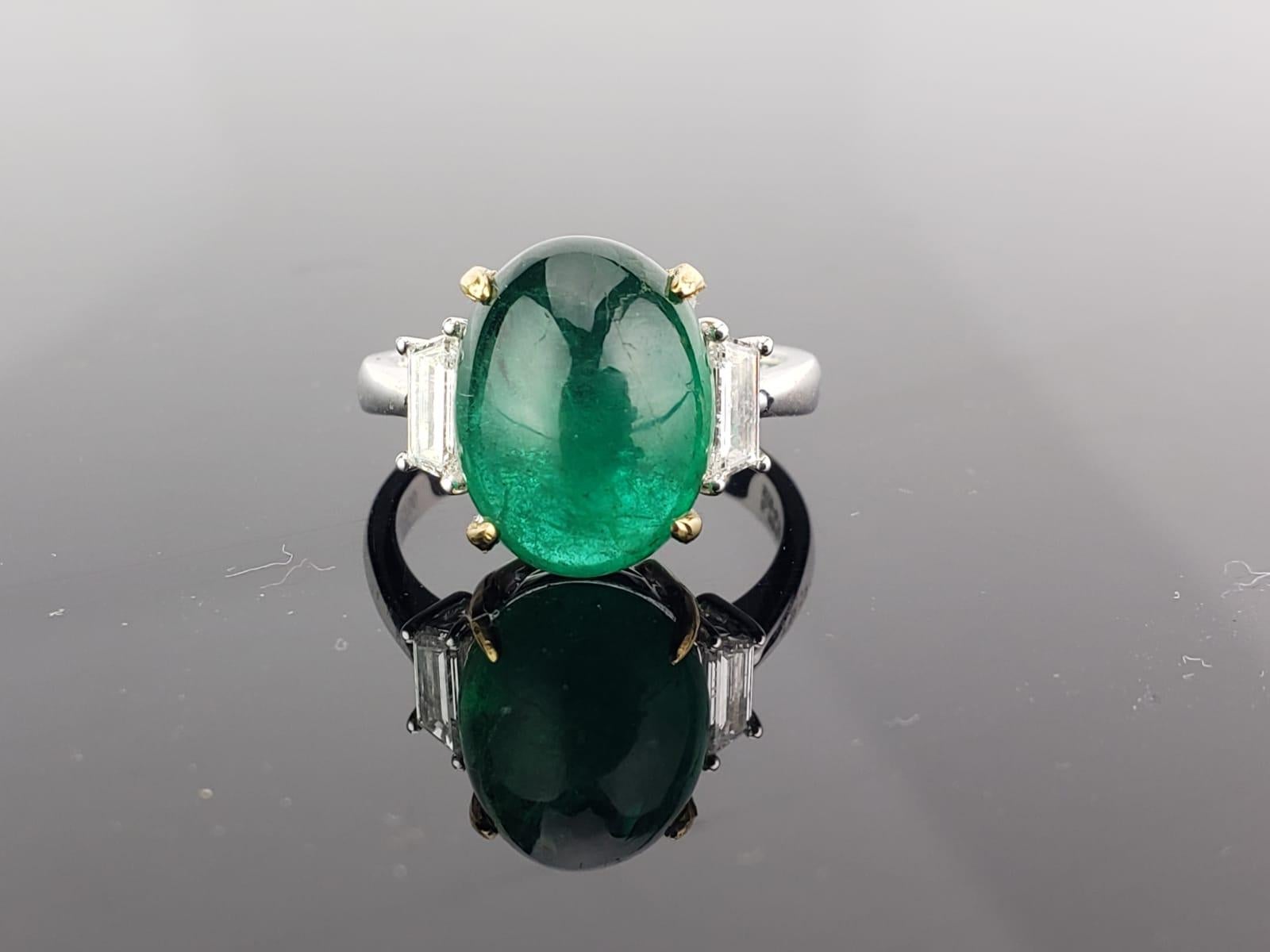 A beautiful three stone ring, with a 7.17 carat lustrous and transparent Zambian Emerald cabochon centre stone and 2 trapeze side stone diamonds; all set in 18K white gold. Currently a ring size US 6, but we can resize the ring for you without