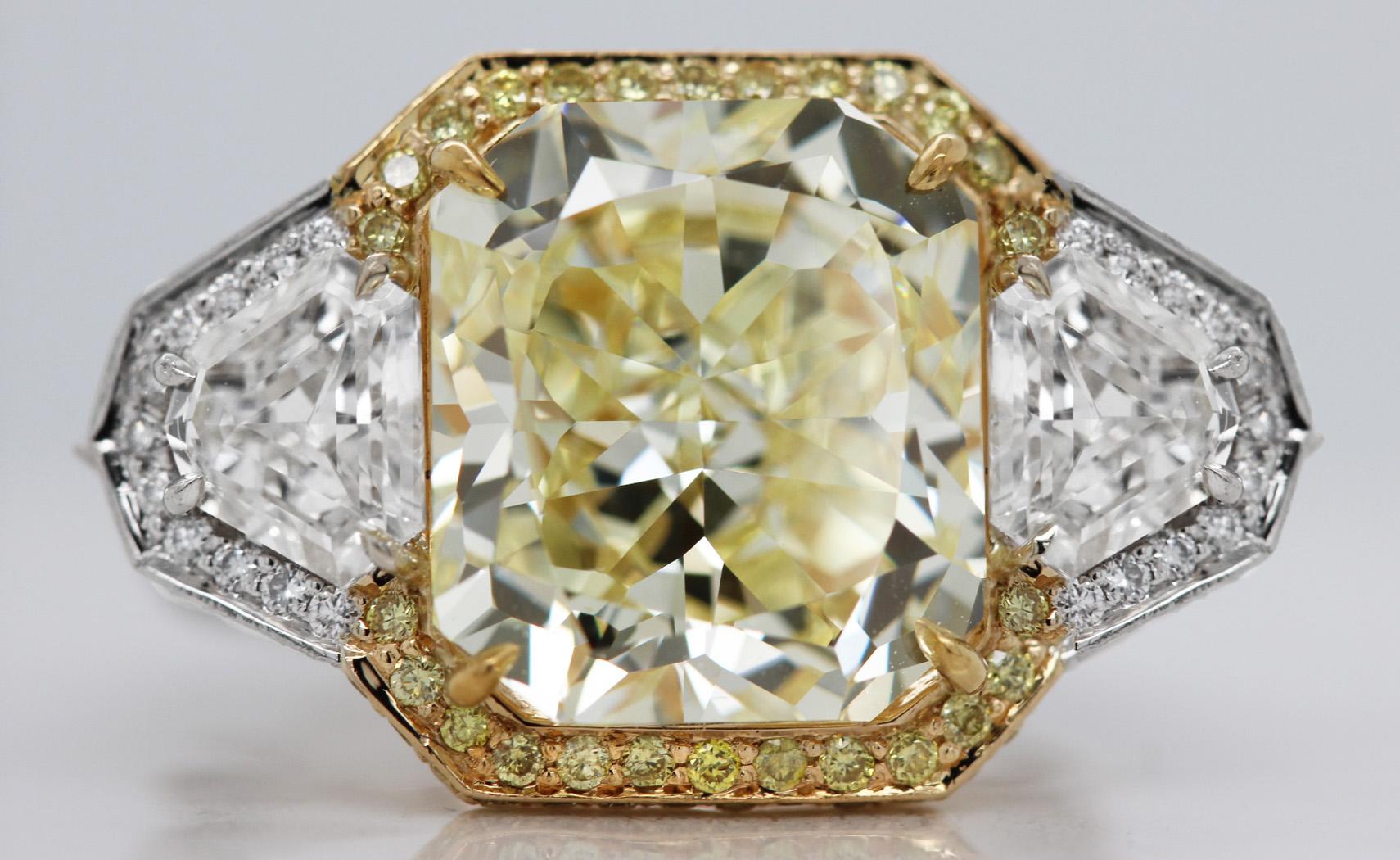 A true show stopper – this art-deco inspired ring features a gorgeous 7.13 carat natural, fancy yellow radiant-cut diamond. Sidled by two white trapezoid-cut diamonds (1.00 TCW), adding to the geometrical look. The overall “clean” look of the ring