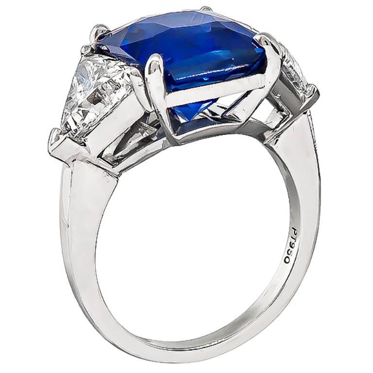 This stunning platinum engagement ring is centered with a lovely faceted square cut sapphire that weighs 7.17ct. The sapphire is flanked by sparkling GIA certified trilliant cut diamonds that weigh 1.03ct and 1.04ct graded H/SI1 and G/SI1. The top