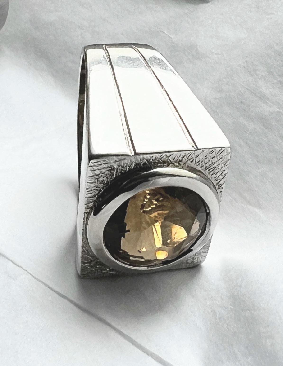 This ring features a natural round-cut citrine, approximately 12.28mm in diameter, displaying a deep golden-brown hue with high transparency. The faceting of the citrine enhances its optical properties, allowing light to interact dynamically with