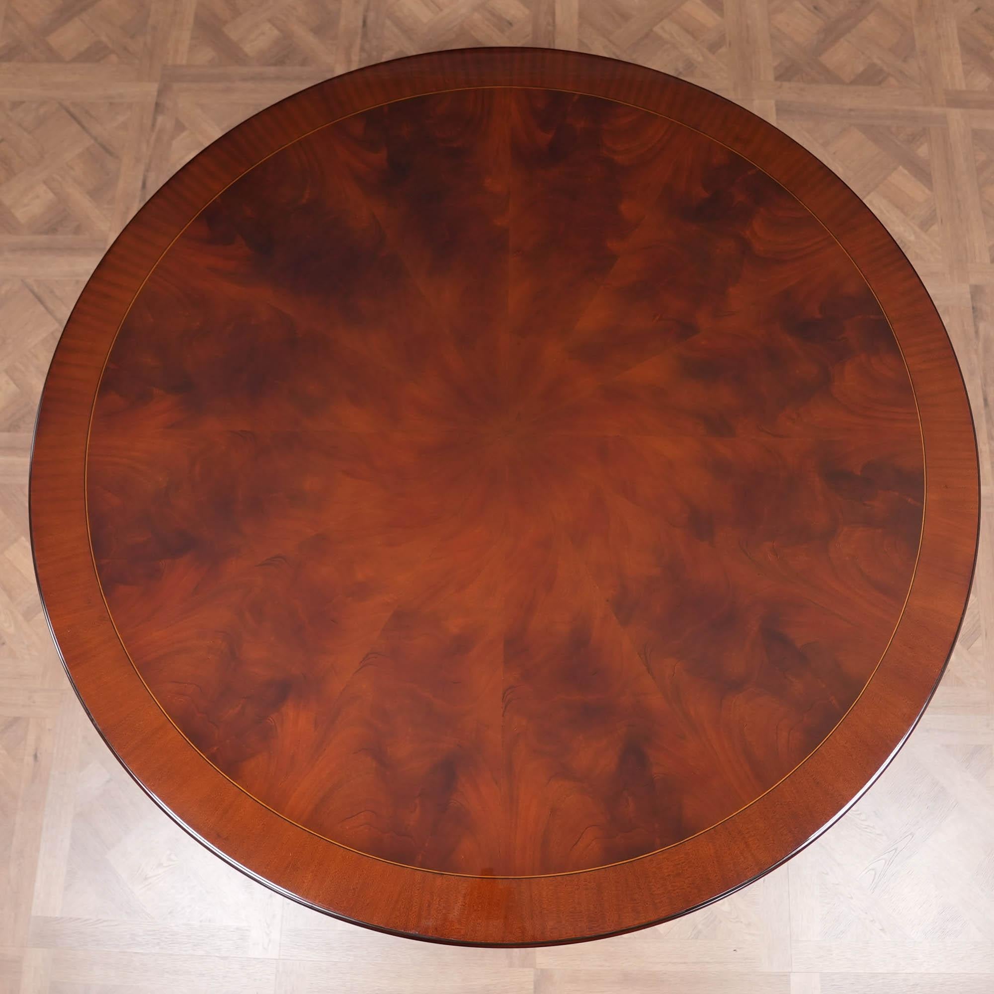 Cette table ronde de 72 pouces est aussi jolie que possible. Une fantastique base aux pieds chantournés et sculptés à la main, exécutée en acajou massif, est reliée à travers la plate-forme à des piliers sculptés et tournés qui sont aussi beaux que