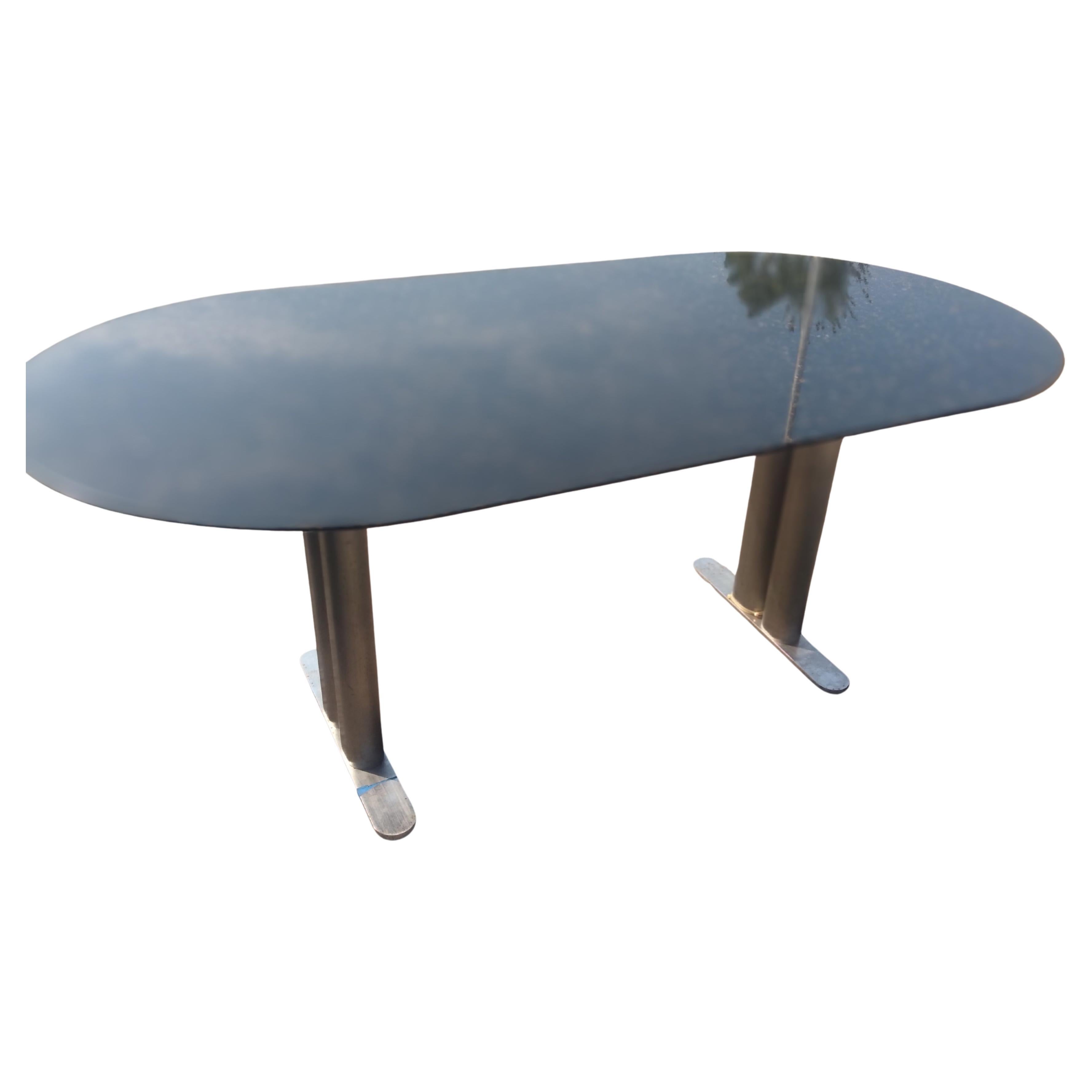 Se trata de una mesa de comedor moderna John Geiger con forma de hipódromo, base de acero inoxidable y tablero de granito.
La parte superior tiene forma de pista de carreras. La base tiene 4 patas que se conectan a una barra de acero que estabiliza