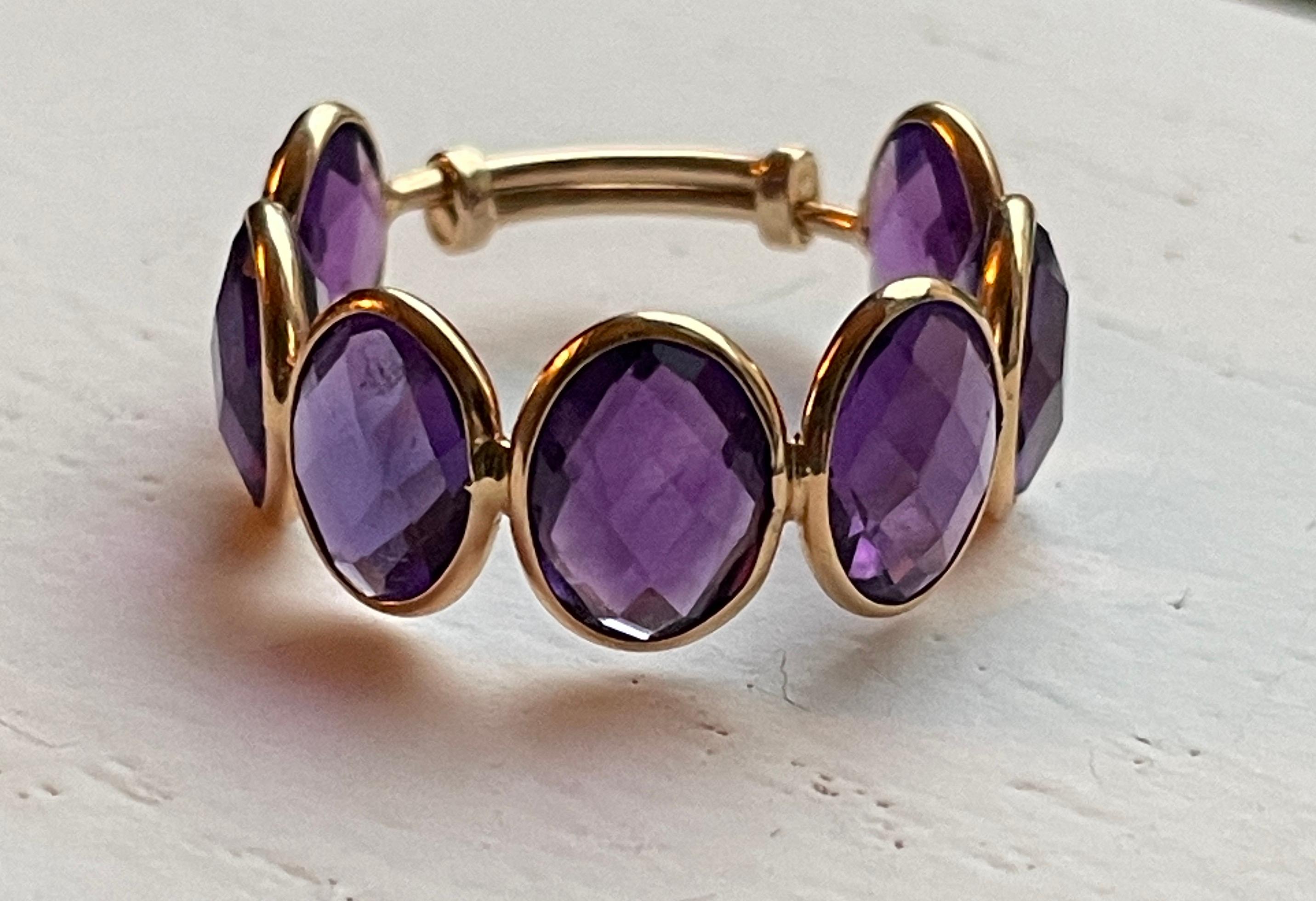 This 18K Gold ring is comprised of 7 checker cut oval Amethyst Stones. The stones are bezel set and checker cut allowing for maximum sparkle and shine. The ring is a size 7 with a built in adjustable sizer which will allow the ring to expand to size