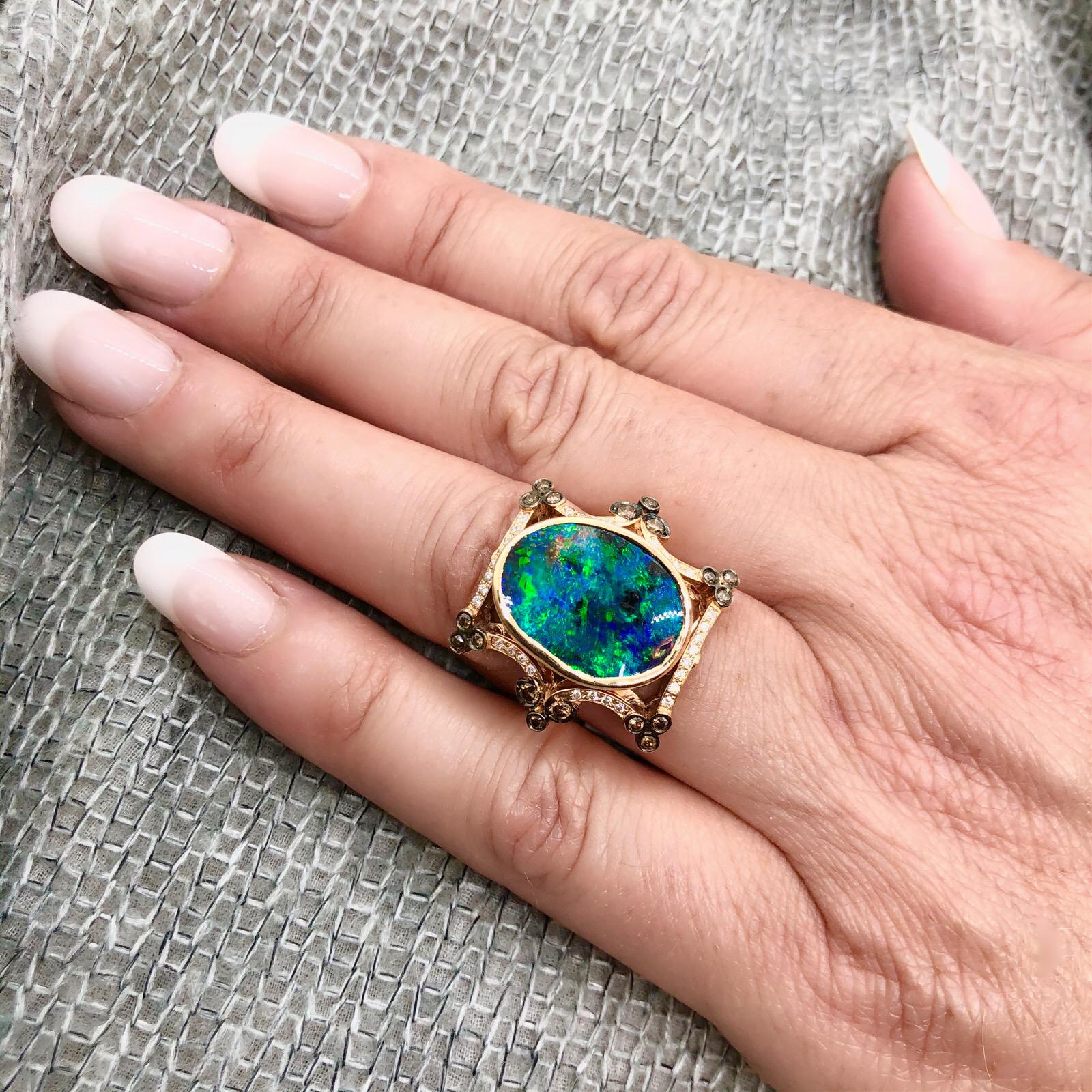 18Kt Rose Gold ring features a 7.23-ct Oval shape Boulder Black Opal with blue & green Play of Color. Accenting the ring are 32 white diamonds totaling 0.20-ctw, and 18 cognac color diamonds totaling 0.30-ctw. The top of the ring measures about 1