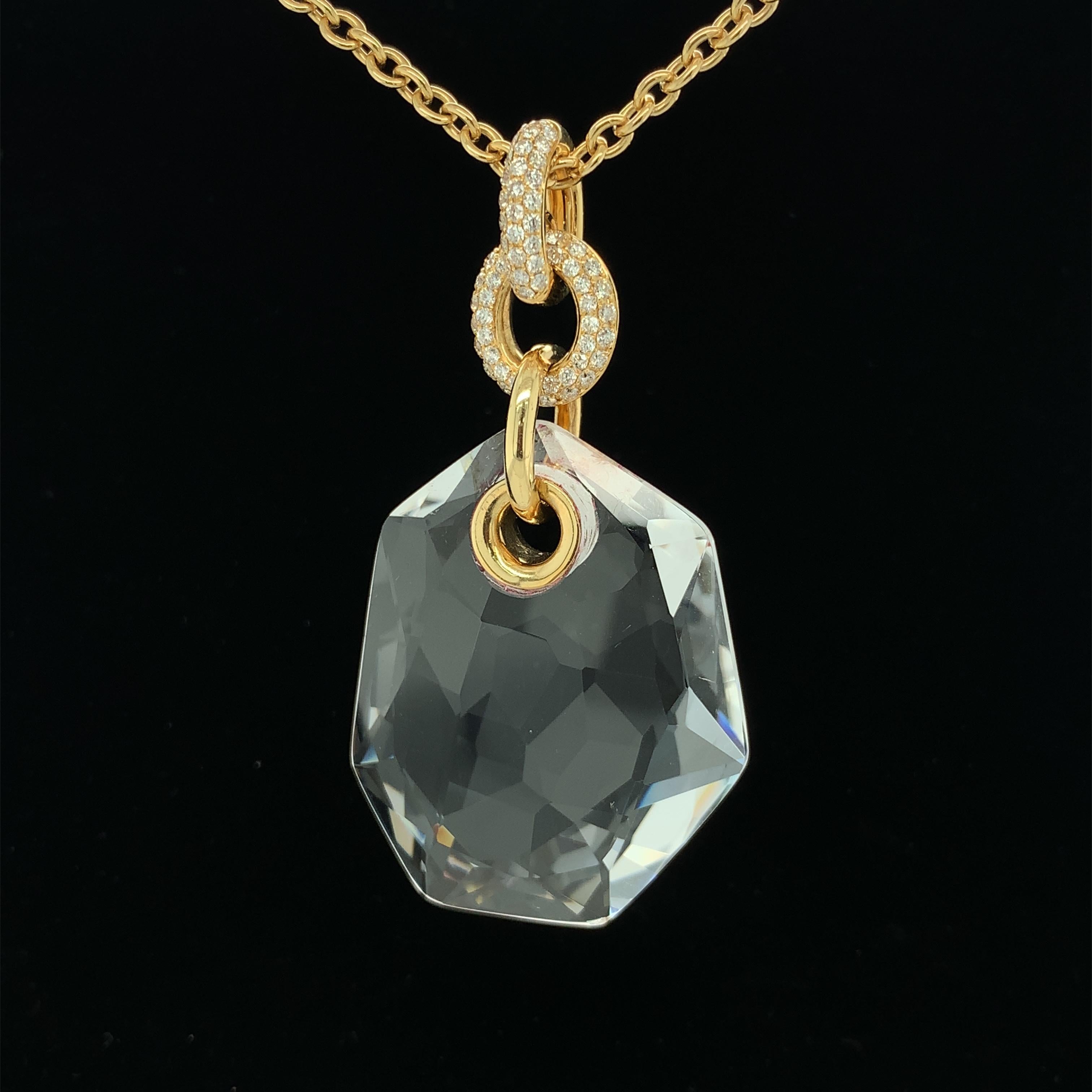 A large asymmetrical piece of faceted rock crystal quartz is featured in this unique pendant. The rock crystal quartz is suspended from links of 18k yellow gold. Two links are pave set with sparkly diamonds; the top link is hinged to open and close