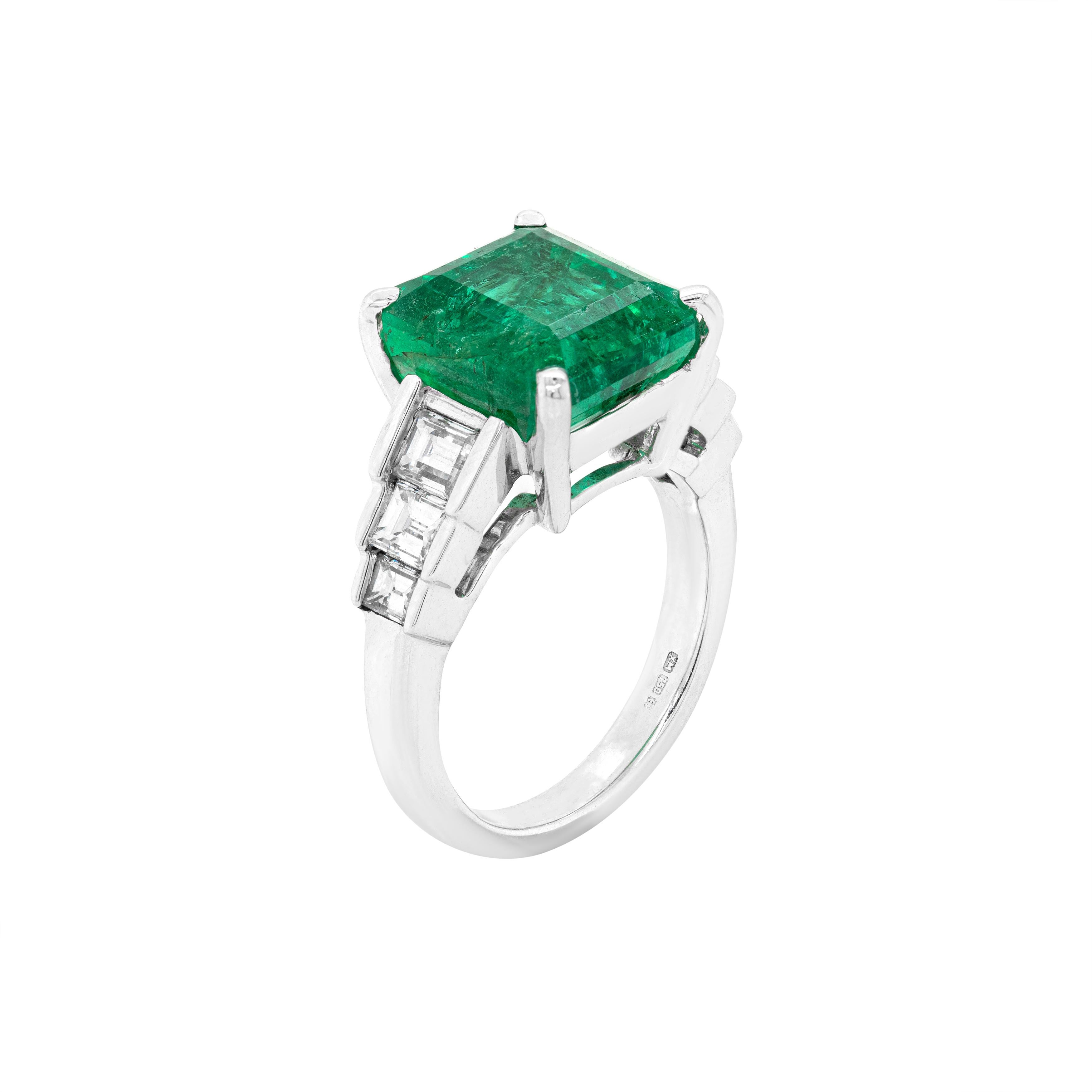 This amazing 18 carat white gold engagement ring features a beautiful 7.24ct emerald cut natural emerald, mounted in a four claw, open back setting. The emerald is accompanied by three baguette cut diamonds on either side, mounted in open back,