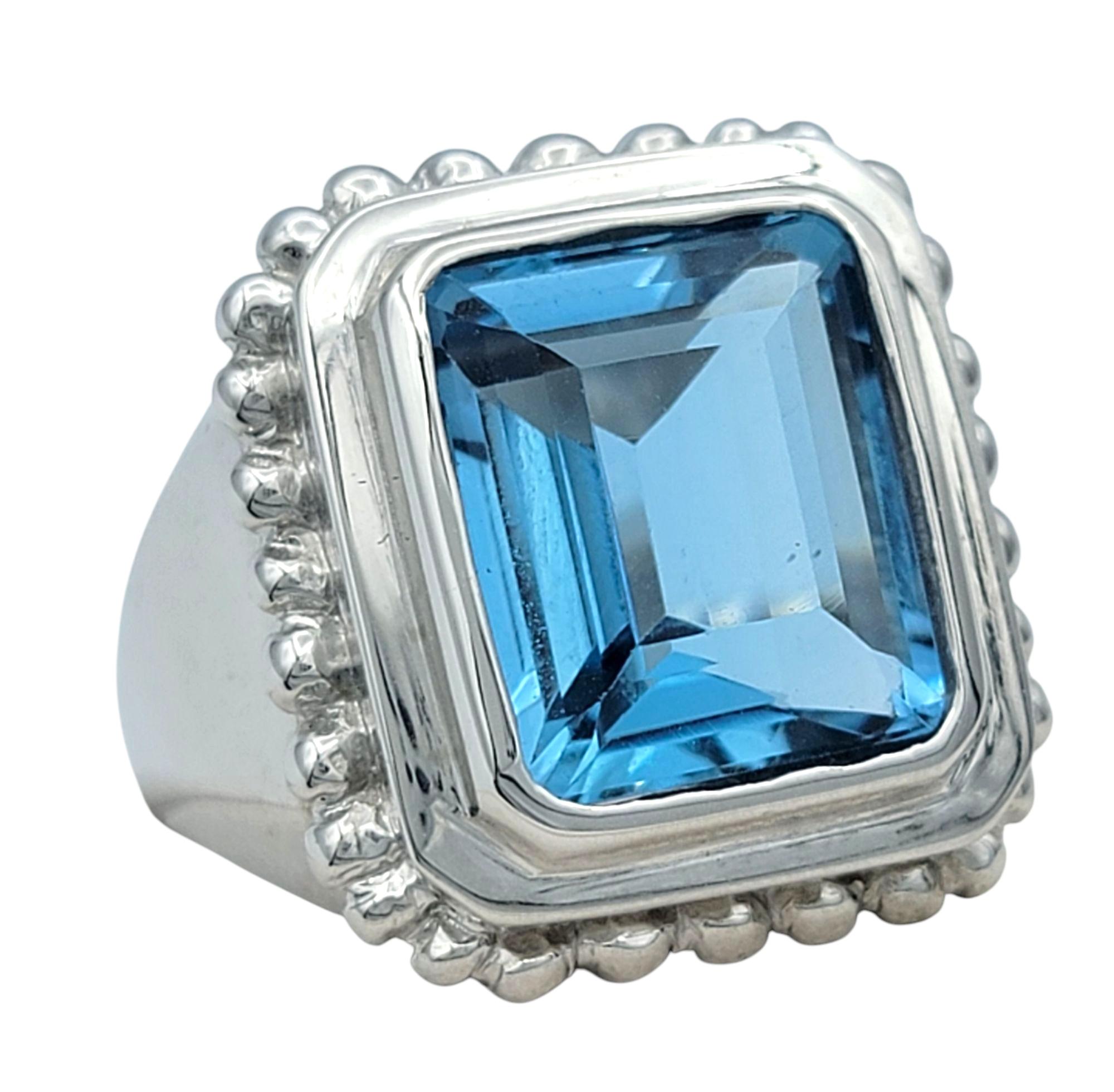 Ringgröße: 6

Dieser kühne und elegante Ring präsentiert einen auffälligen Blautopas im Smaragdschliff von 7,27 Karat, eingefasst in glänzendes 14-karätiges Weißgold. Der leuchtende, satte Farbton des Topas wird durch eine Lünettenfassung mit