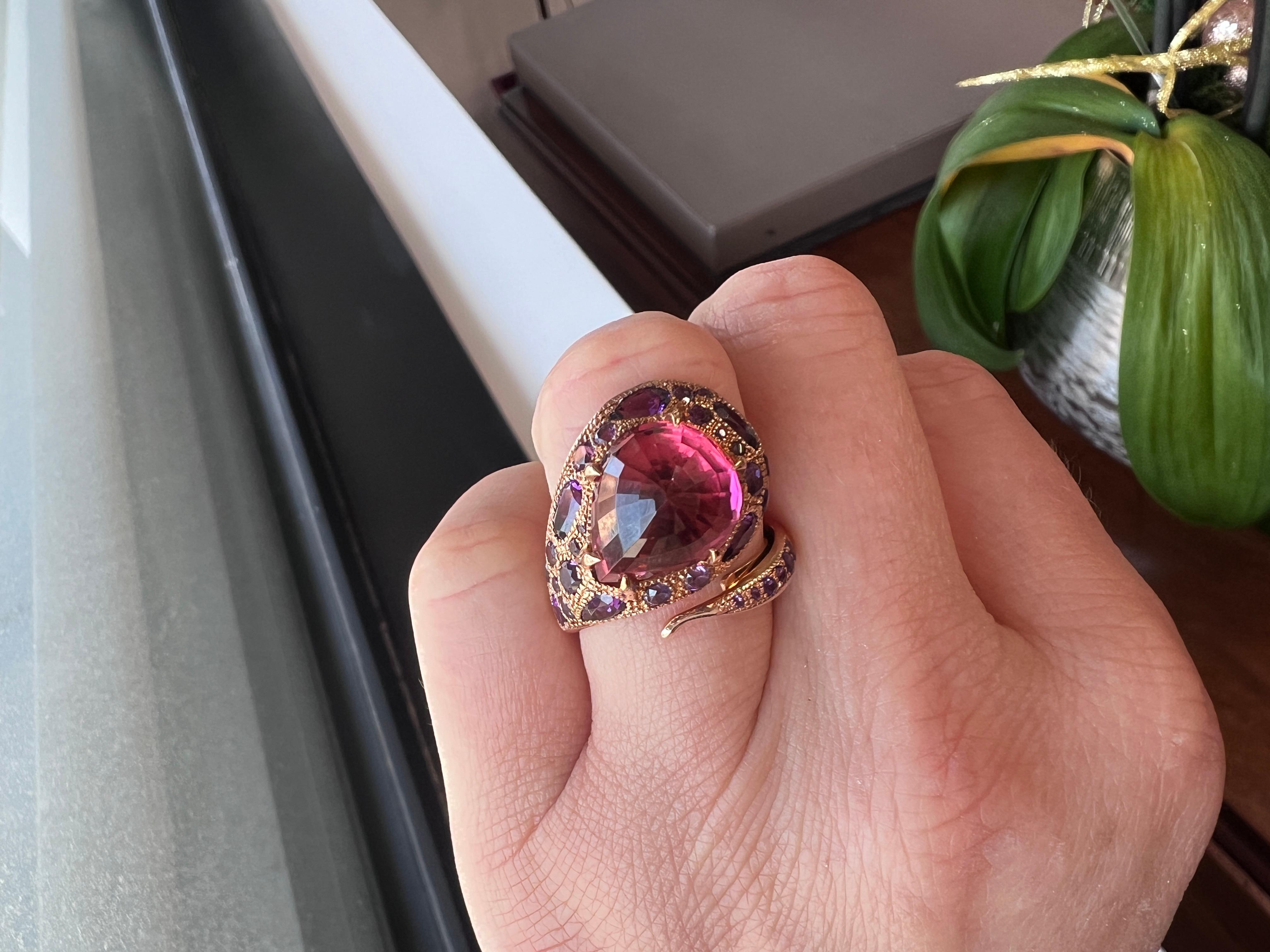 Adam Neeley, 14K rose gold dome fashion ring showcases a stunning 7.27-carat table-set rubellite tourmaline surrounded by amethysts set in rose gold. The centerpiece is the 7.27-carat faceted bright rubellite tourmaline adorned by a vibrant halo of