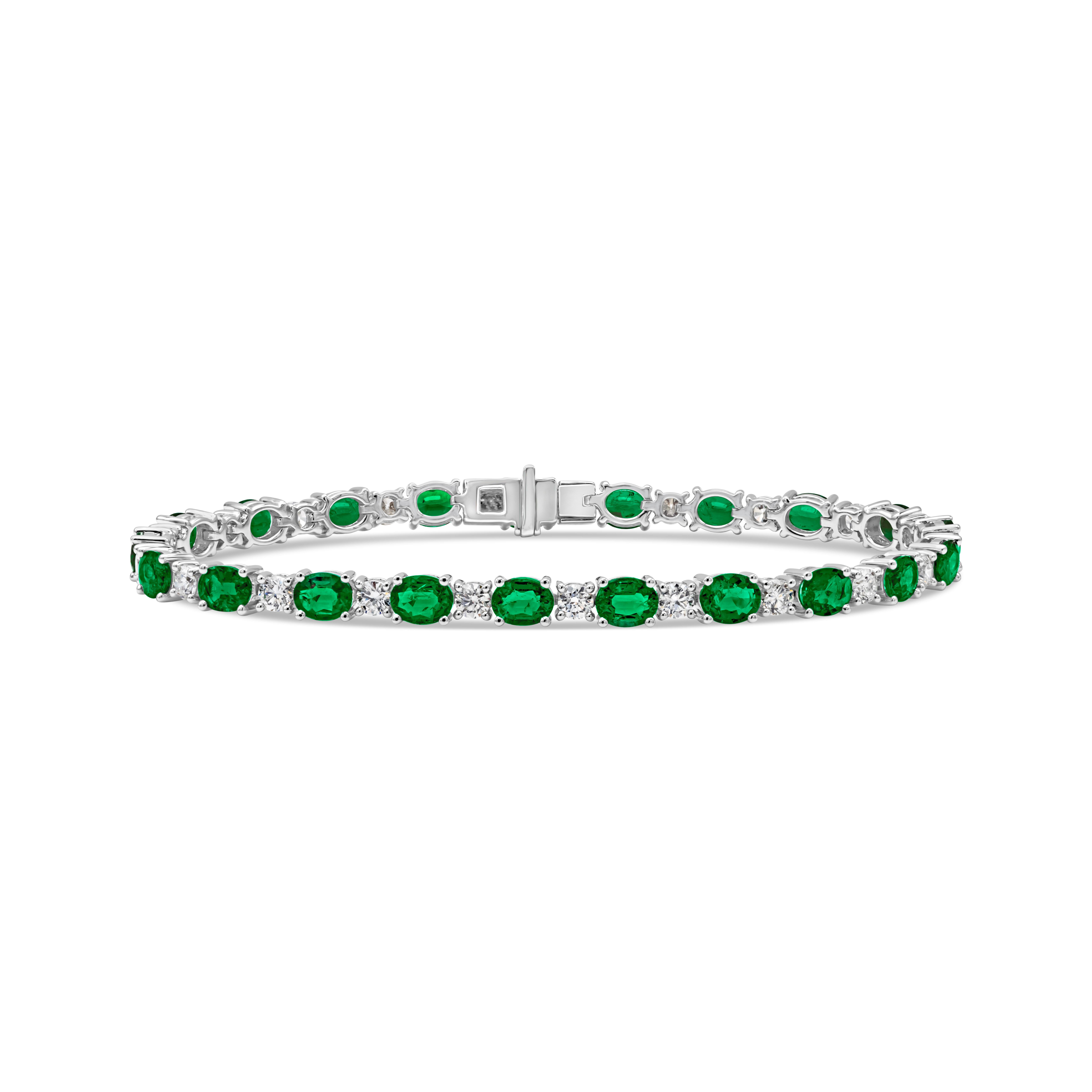 An exquisite and elegant tennis bracelet showcasing a color-rich oval cut green emerald weighing 5.33 carats total, set in a classic four prong setting. Evenly spaced by brilliant round cut diamonds weighing 1.94 carats total, G color and VS2 in