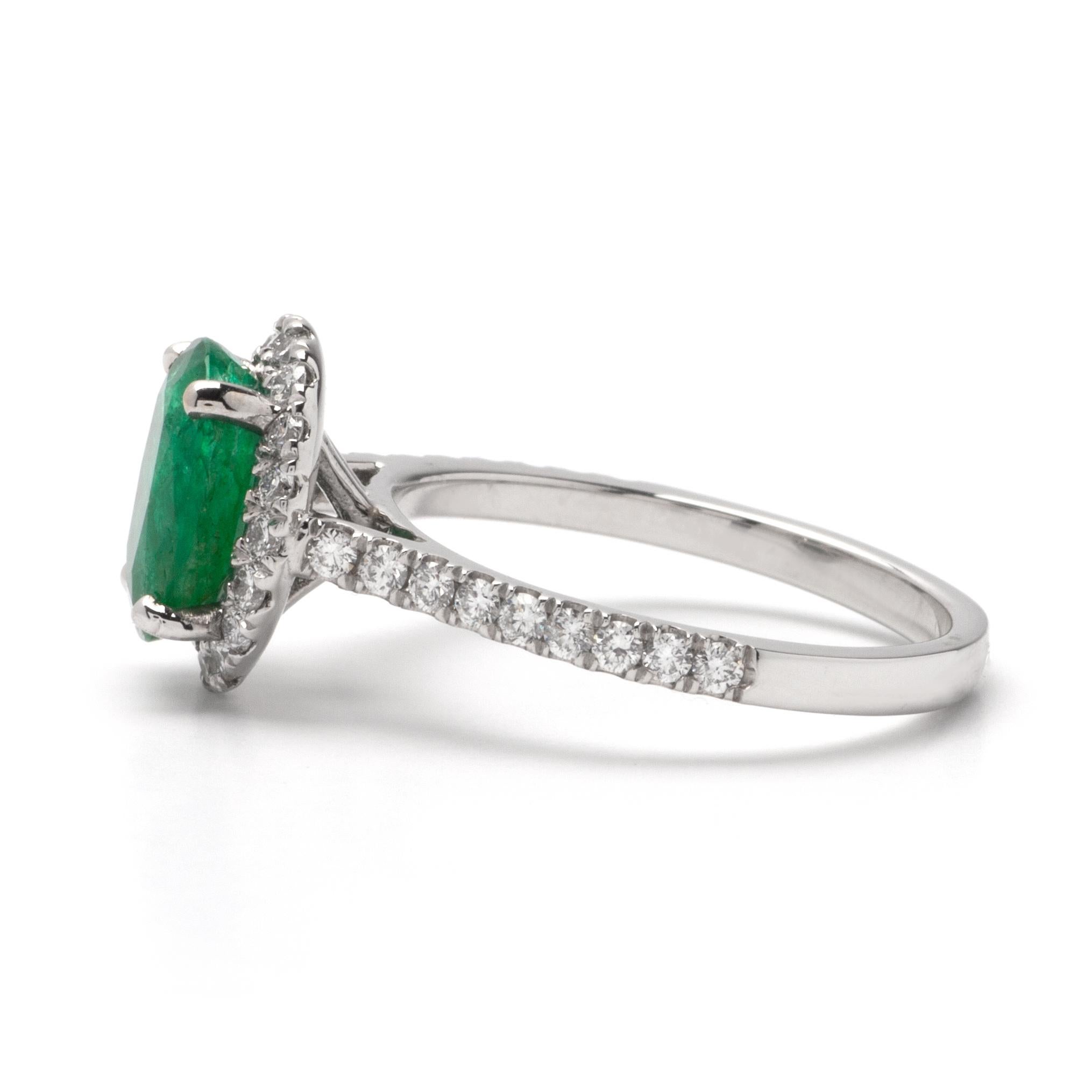 This ring features a halo design of G color, VS1 clarity, and .50ct Round side diamonds set in 14K white gold. The center gemstone is a 1.77ct oval green emerald. 