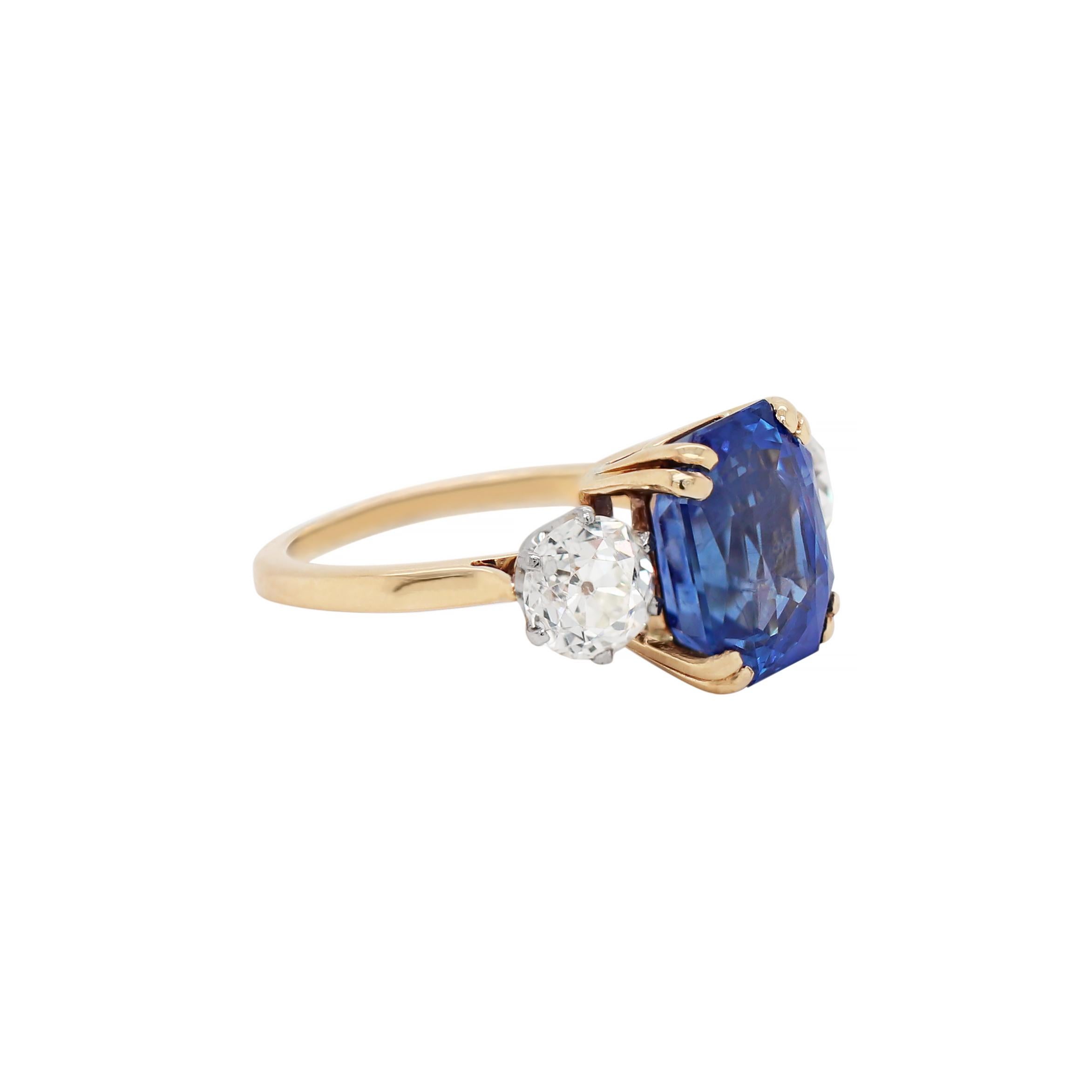Beautiful handmade engagement ring set with a natural unheated blue sapphire weighing a total of 7.29 carats mounted in a four double claw, open back setting, accompanied by two old mine cut diamonds, one on either side, weighing a total of 1.80
