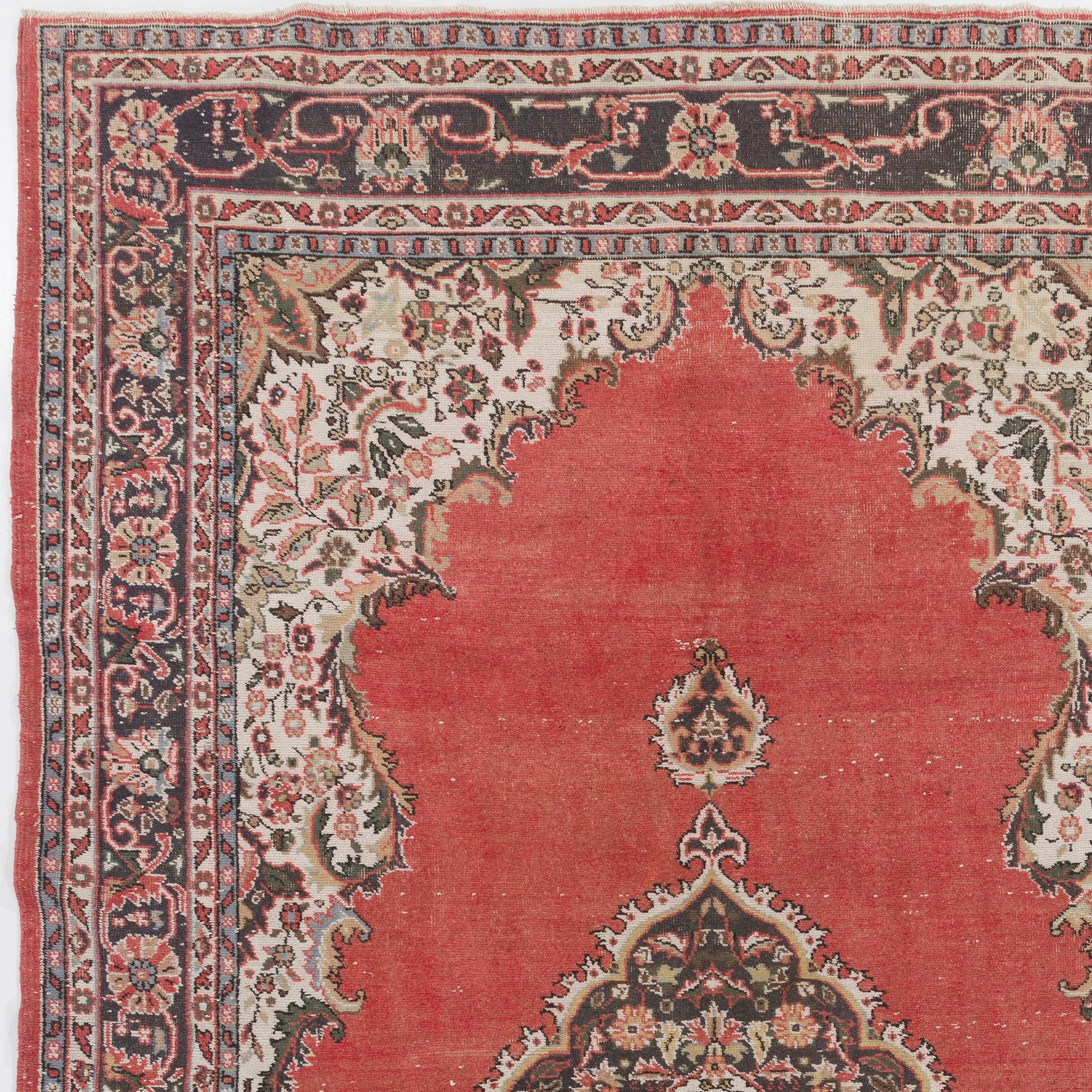 A fine vintage hand knotted Turkish Oushak rug from the 1960s featuring a central floral medallion in dull navy blue against a plain warm madder red field, finished off with spandrels in cream and a border in olive green and navy blue both filled