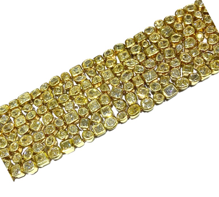 18 karat yellow, gold bezel set diamond bracelet consists of 217 multi-shaped diamonds. Each diamond is approximately 1/3 of a carat with shapes of round, pear, princess, marquis, ovals, and Emerald cuts. Each stone is set, with precision and