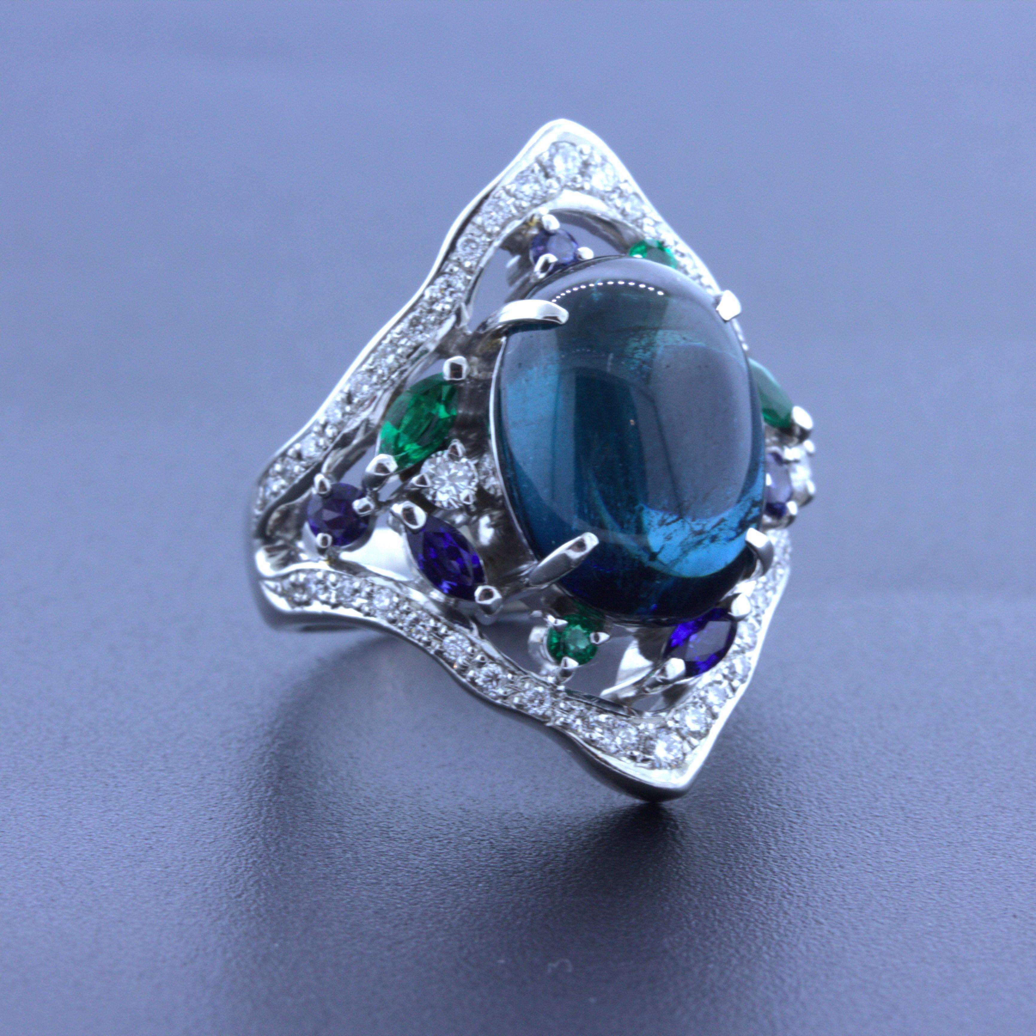 An elegant platinum ring featuring a 7.32 carat indicolite tourmaline. It has the ideal rich slightly greenish-blue color that makes this gem so popular. It is complemented by round and marquise-shape emeralds and sapphires set around the tourmaline