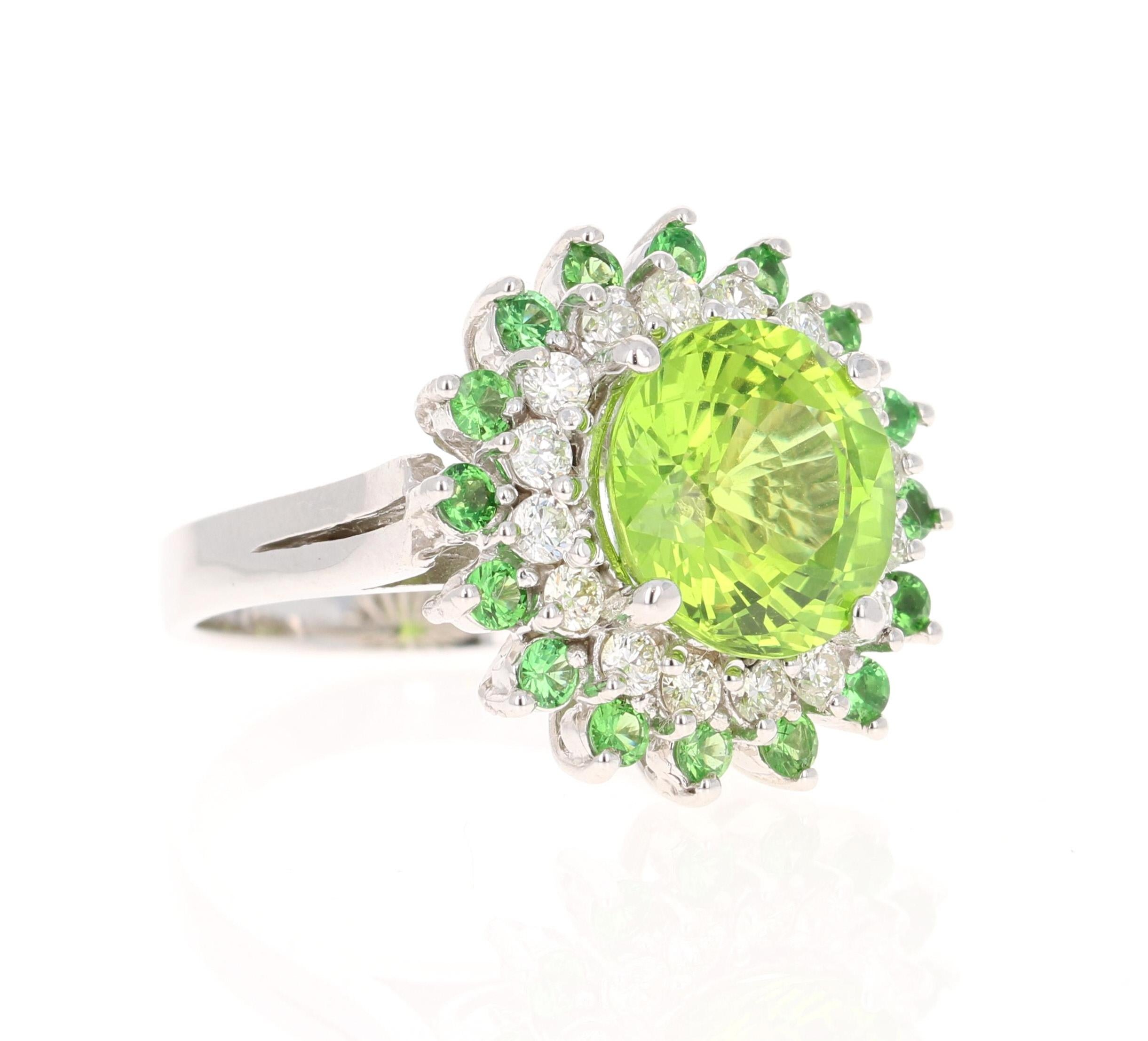 This ring has a Round Cut Natural Peridot that weighs 6.01 carats. It is surrounded by 16 Round Cut Natural Diamonds that weigh 0.62 Carats, (Clarity: VS, Color: H) and 16 Round Cut Natural Tsavorites that weigh 0.70 carats. 
The total carat weight