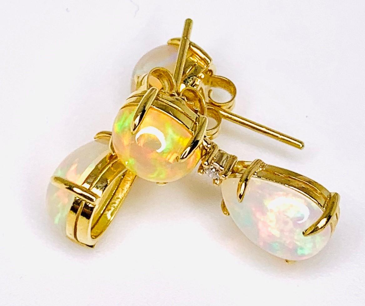 These elegant dangle earrings feature over 7 carats of pear and oval shaped opals, set with 18k yellow gold posts and accented with diamonds! The colorful gems are set in a timeless drop design, and the unique personality of opal makes them so