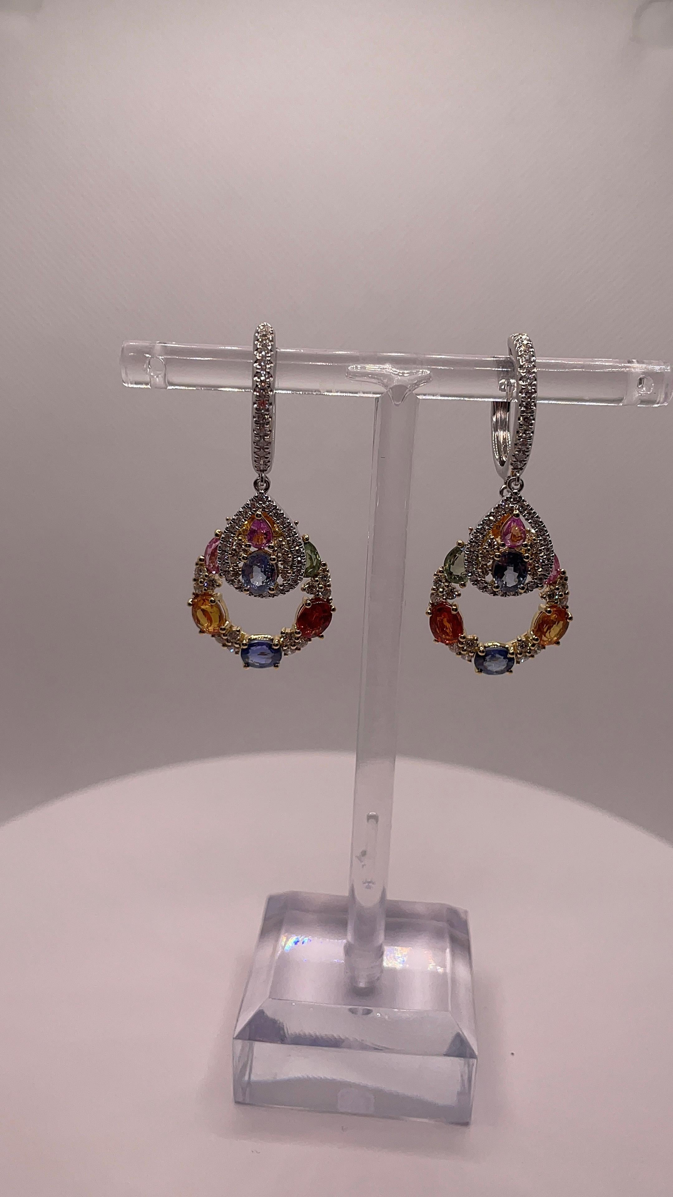 Réalisées en luxueux or blanc 18 carats, ces boucles d'oreilles sont une célébration radieuse de la couleur et de la brillance. Ils comportent 16 saphirs naturels de taille ovale dans un spectre de teintes vives, pesant un total de 7,341 carats. Les