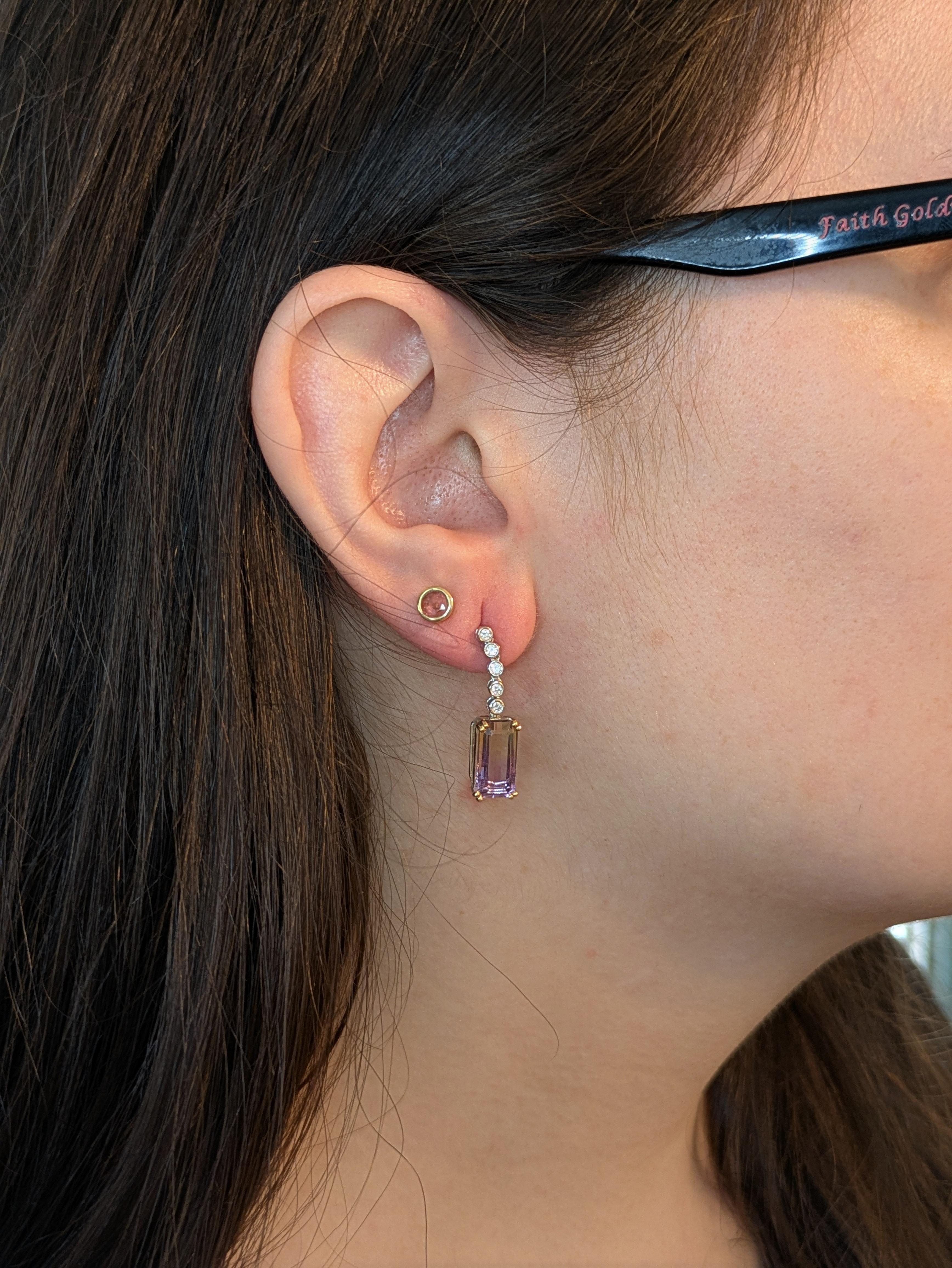 These 7.35cts Ametrine Diamond Drop Earrings in 14K Gold are a perfect blend of elegance and sophistication. Featuring beautiful emerald-cut ametrine gemstones, each measuring 13x6.5mm, these earrings showcase the rare and stunning bicolor