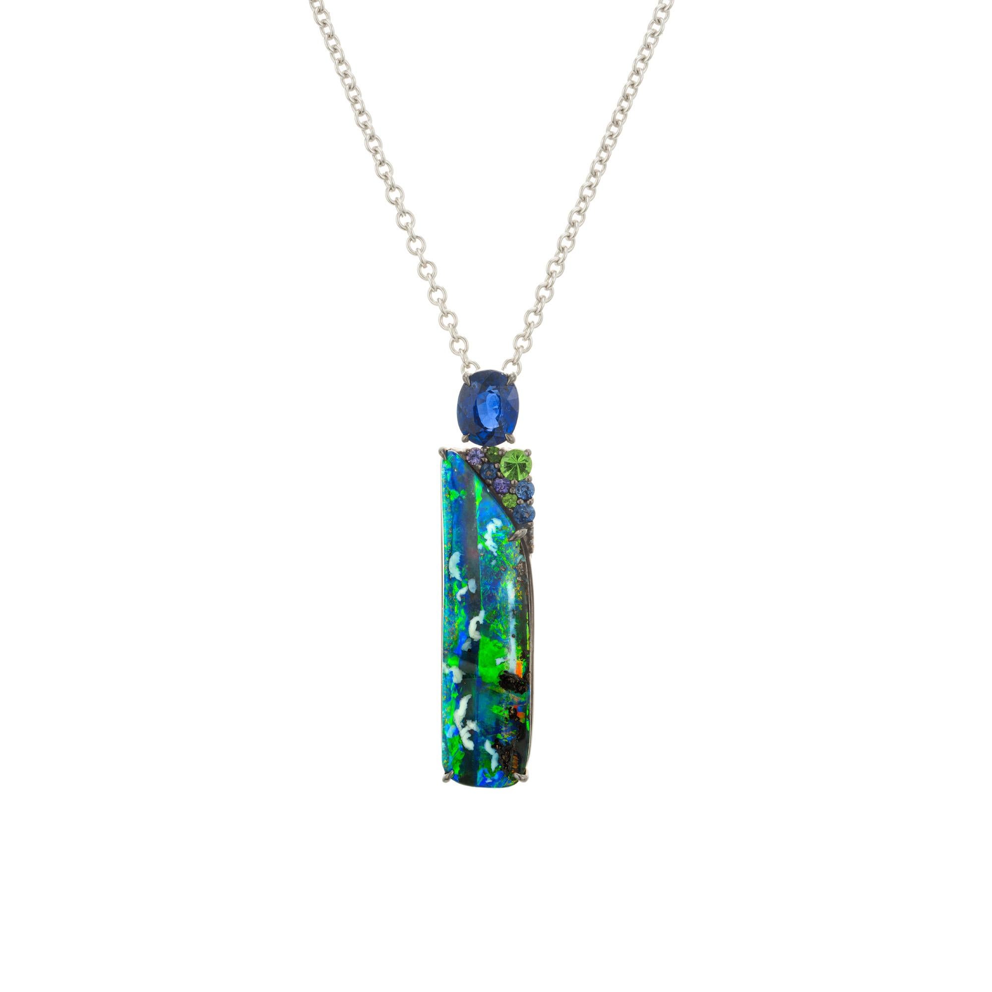Black opal and sapphire pendant necklace. Stunning rectangular blue and green black 7.37ct opal, accented by a oval blue .87ct sapphire, 5 round blue sapphires and 3 round green garnets. The opal is more of a freeform shape with a natural, strong